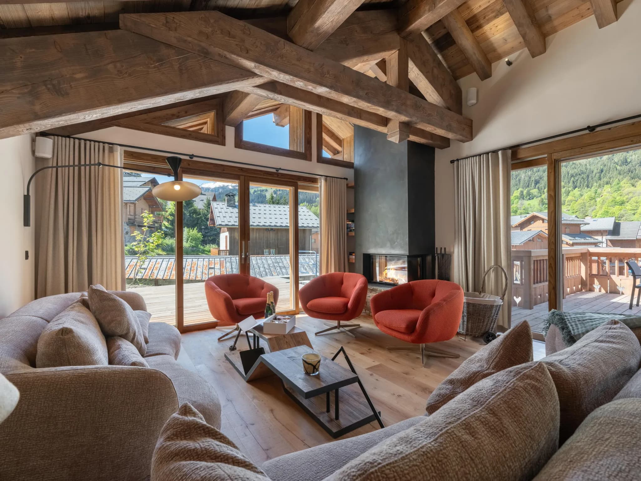 Lounge with fireplace, three orange swivel chairs and sofa facing terrace doors