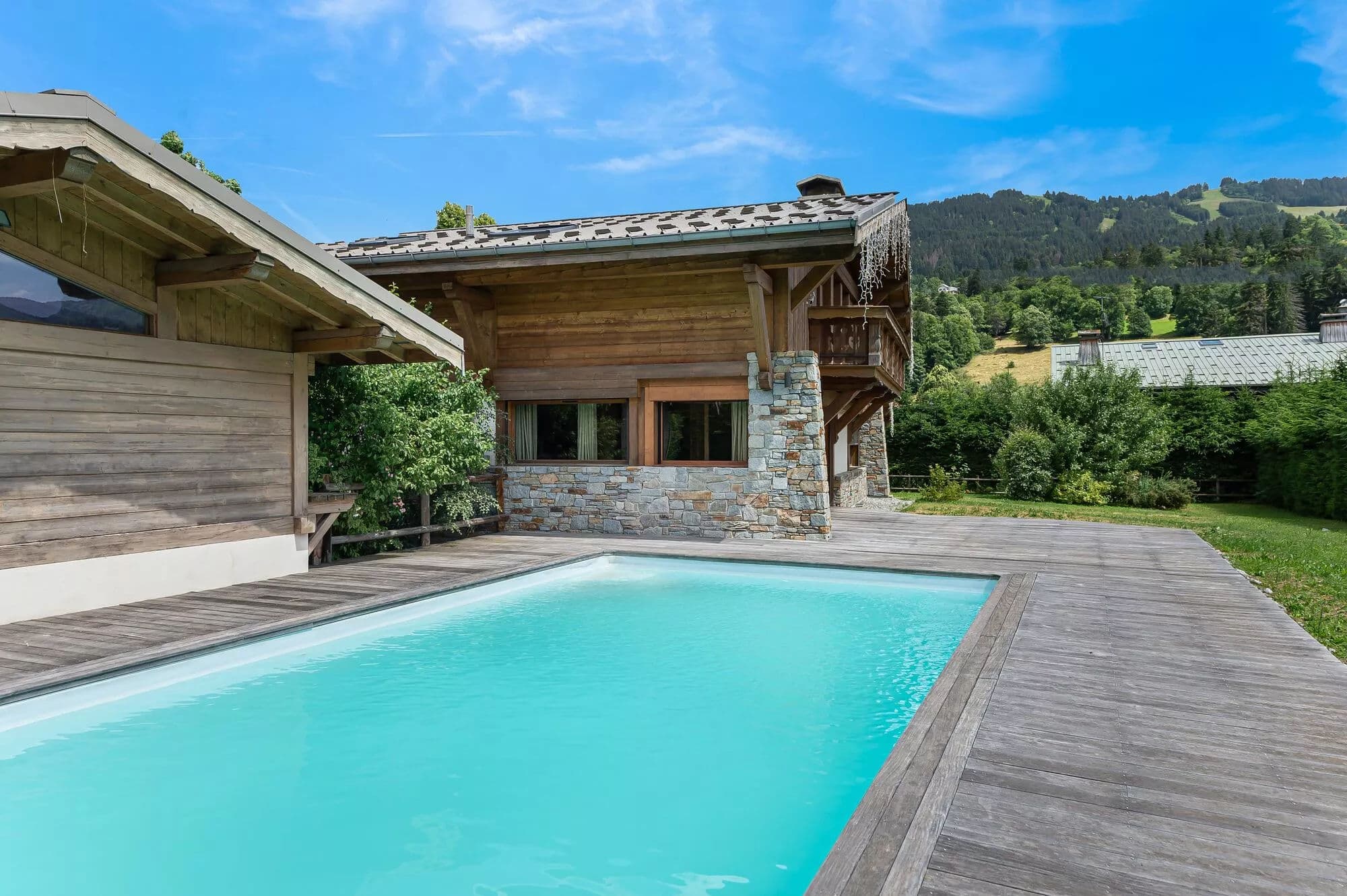 Heated outdoor swimming pool with timber deck and mountain surroundings
