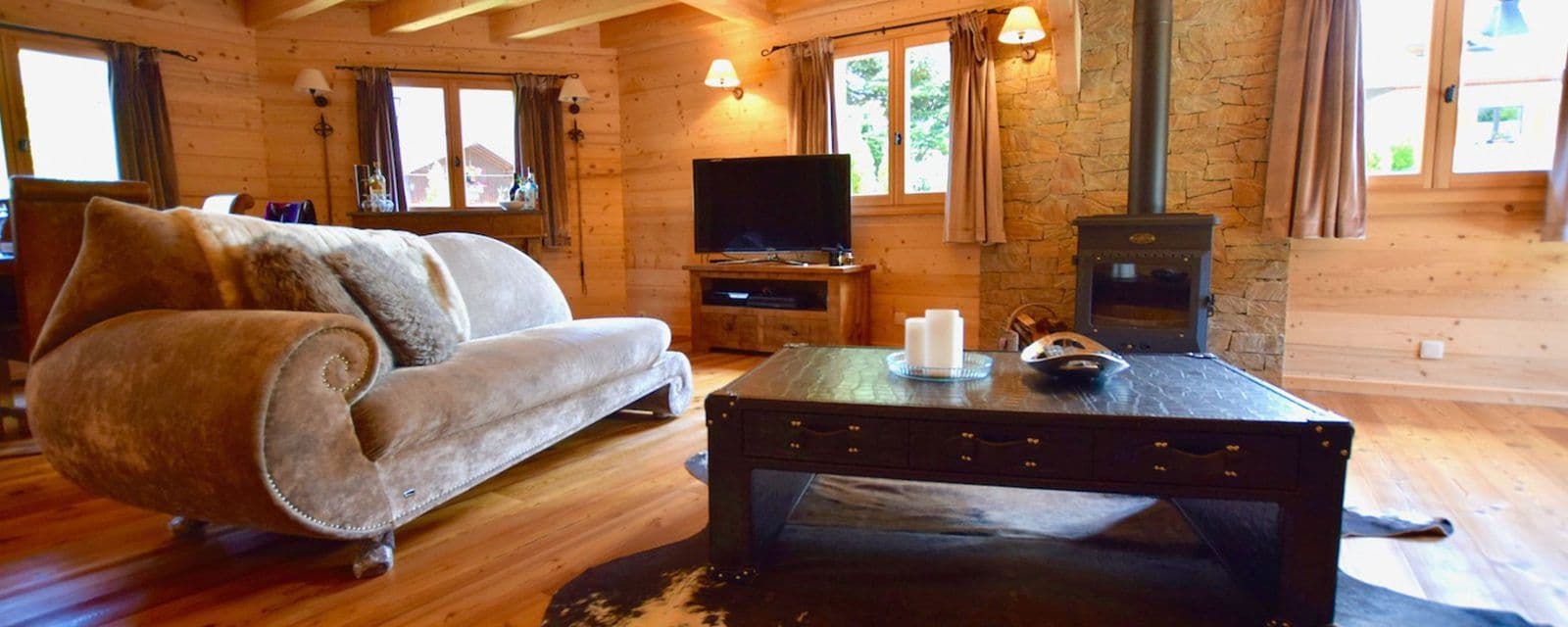 Open-plan lounge with two sofas, a log burner and television