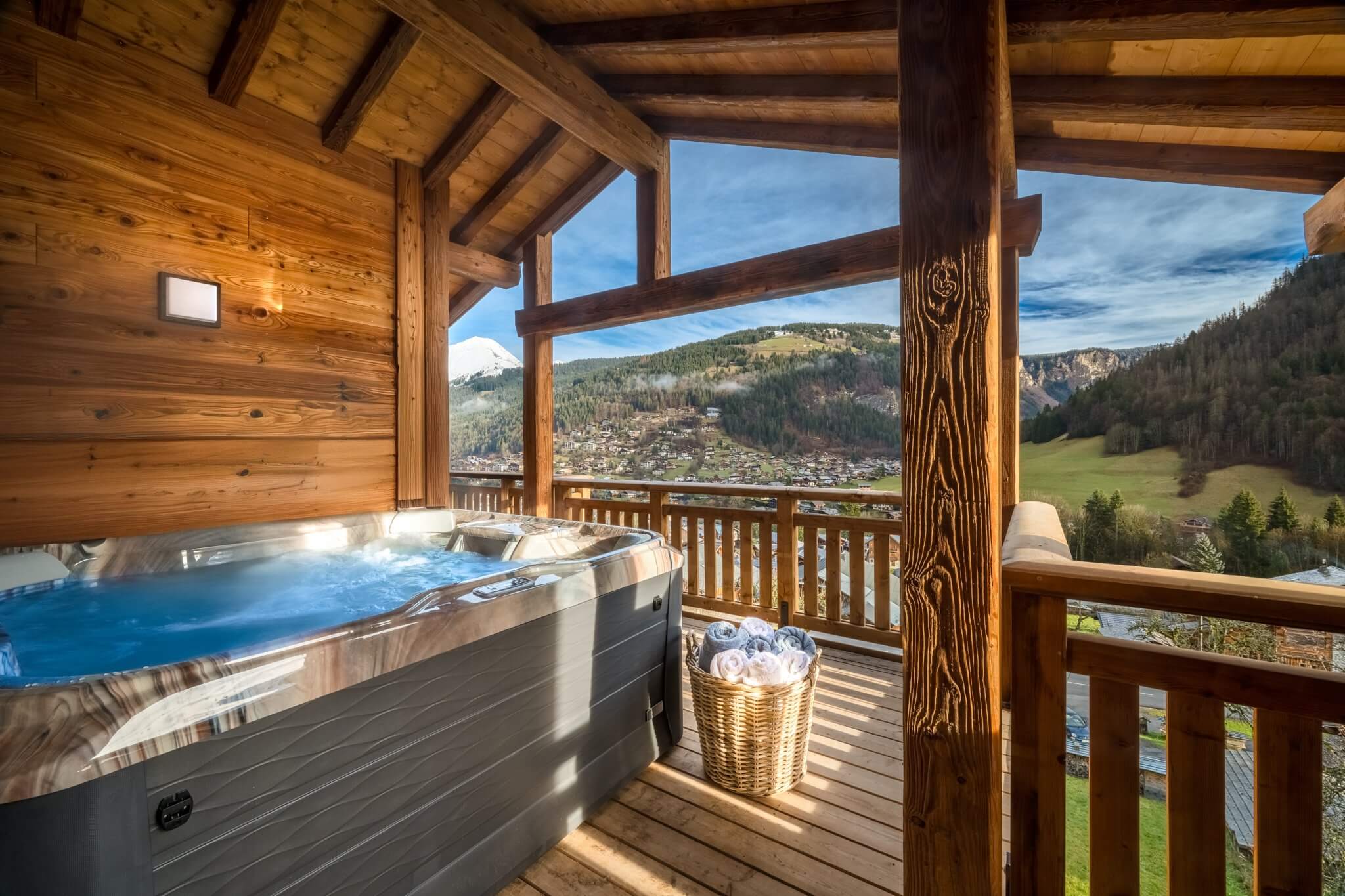 Outdoor hot tub on a covered balcony overlooking the village and mountains