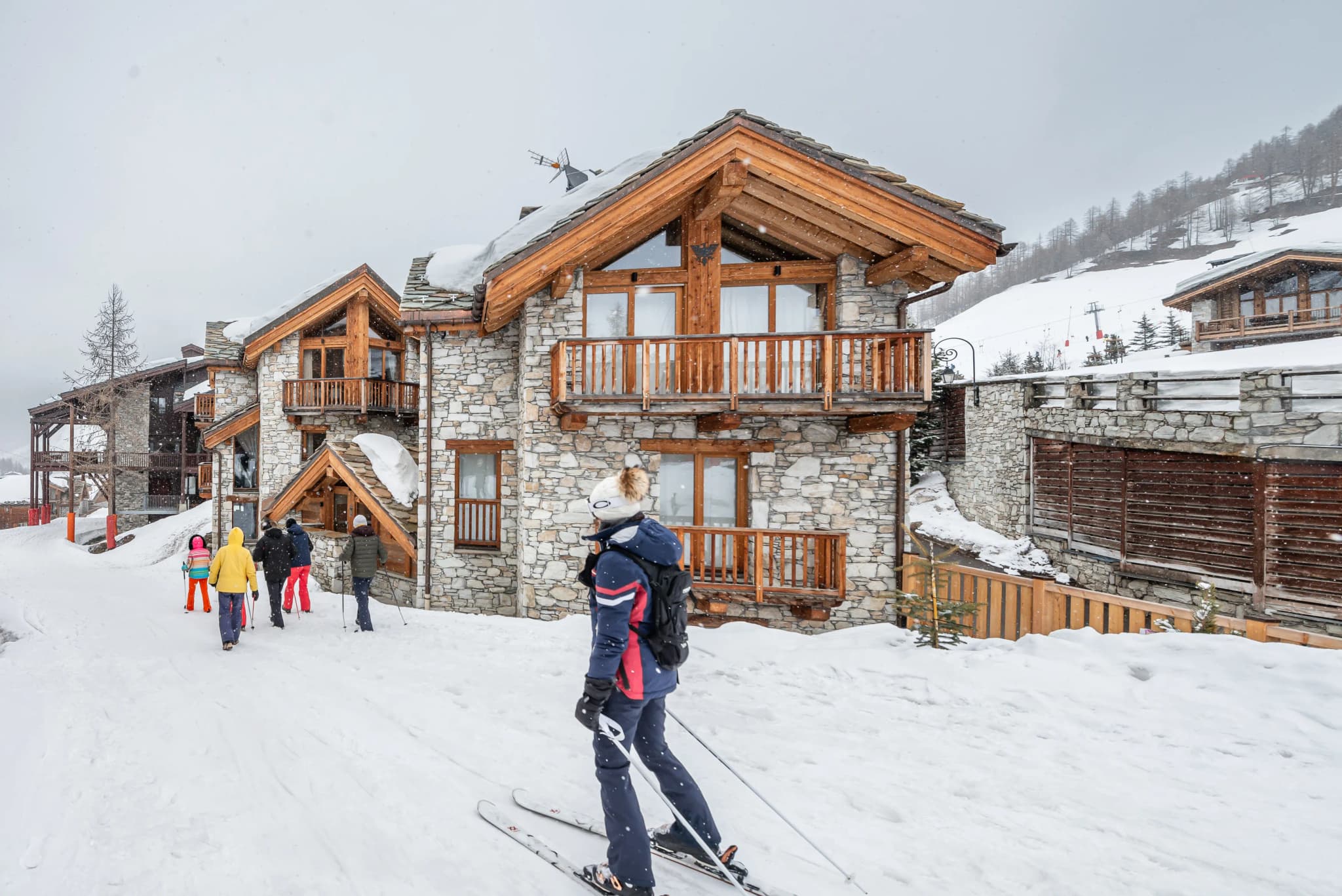 Chalet beside the snow-covered piste with skiers outside
