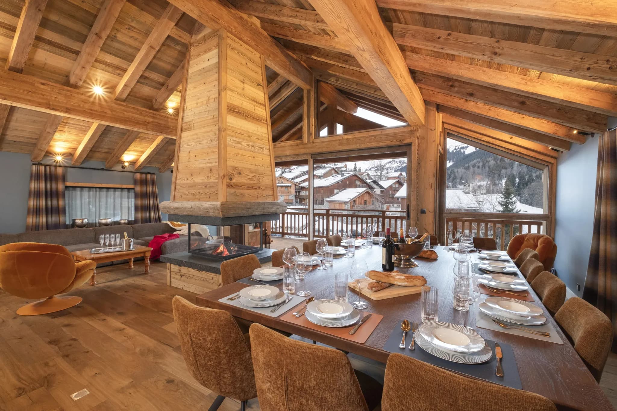 Dining table with 12 chairs beside central fireplace and mountain views