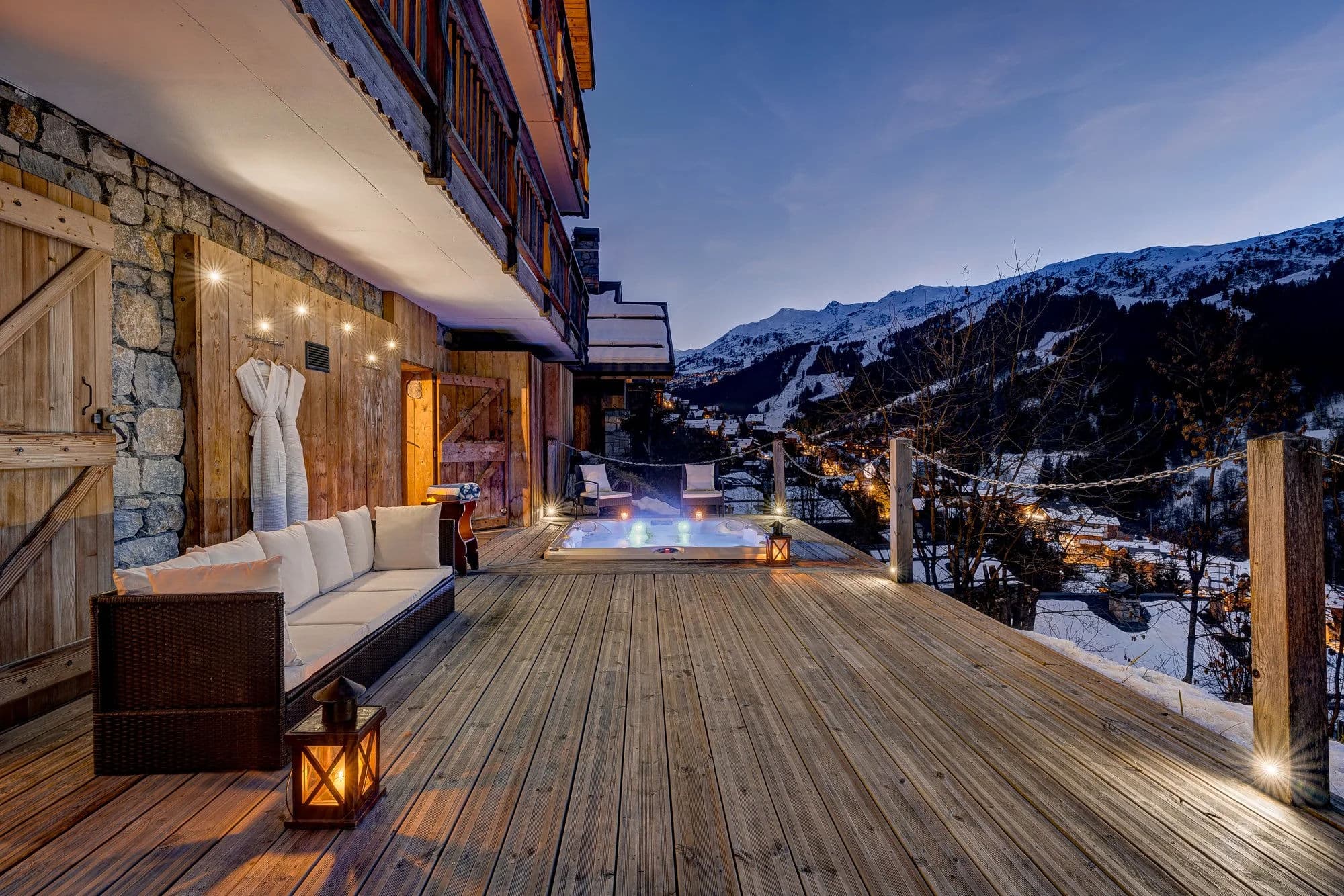 Heated outdoor hot tub on expansive deck; snow-covered alpine valley views