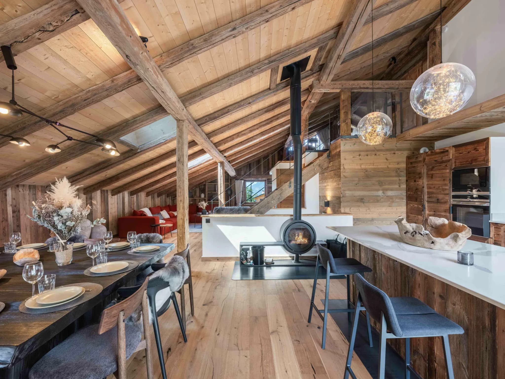 Dining table and breakfast bar beside a freestanding wood stove under exposed beams