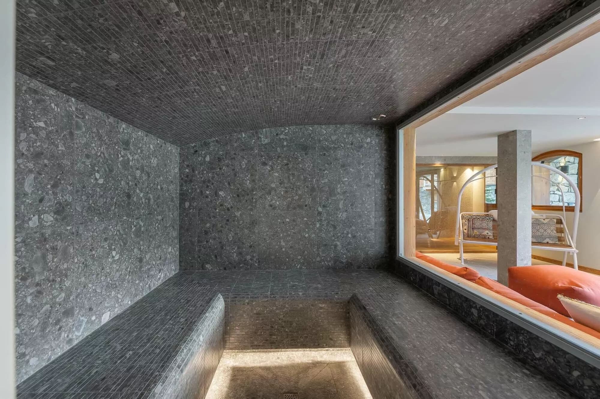 Tiled hammam with bench seating and a window to the wellness area