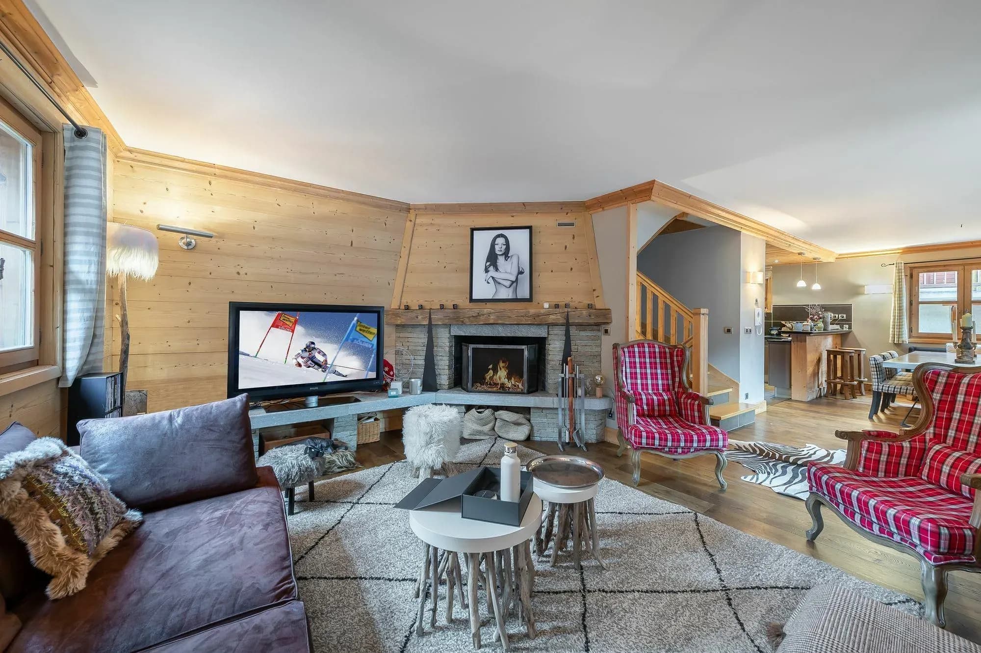 Living room with stone fireplace, TV, leather sofa and two red tartan armchairs