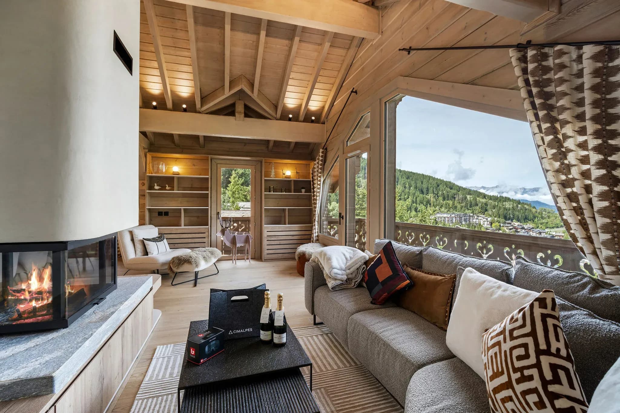 Lounge with corner sofa, glass-fronted fireplace and mountain view through large window