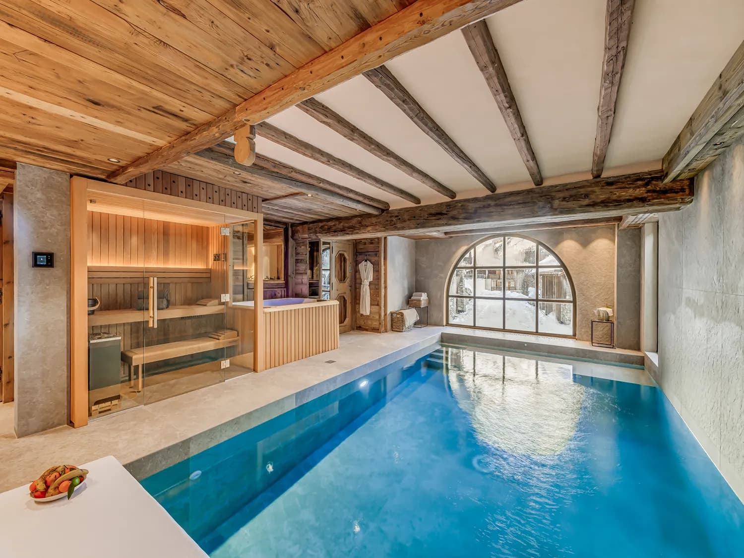 Indoor swimming pool beside the sauna and large arched window