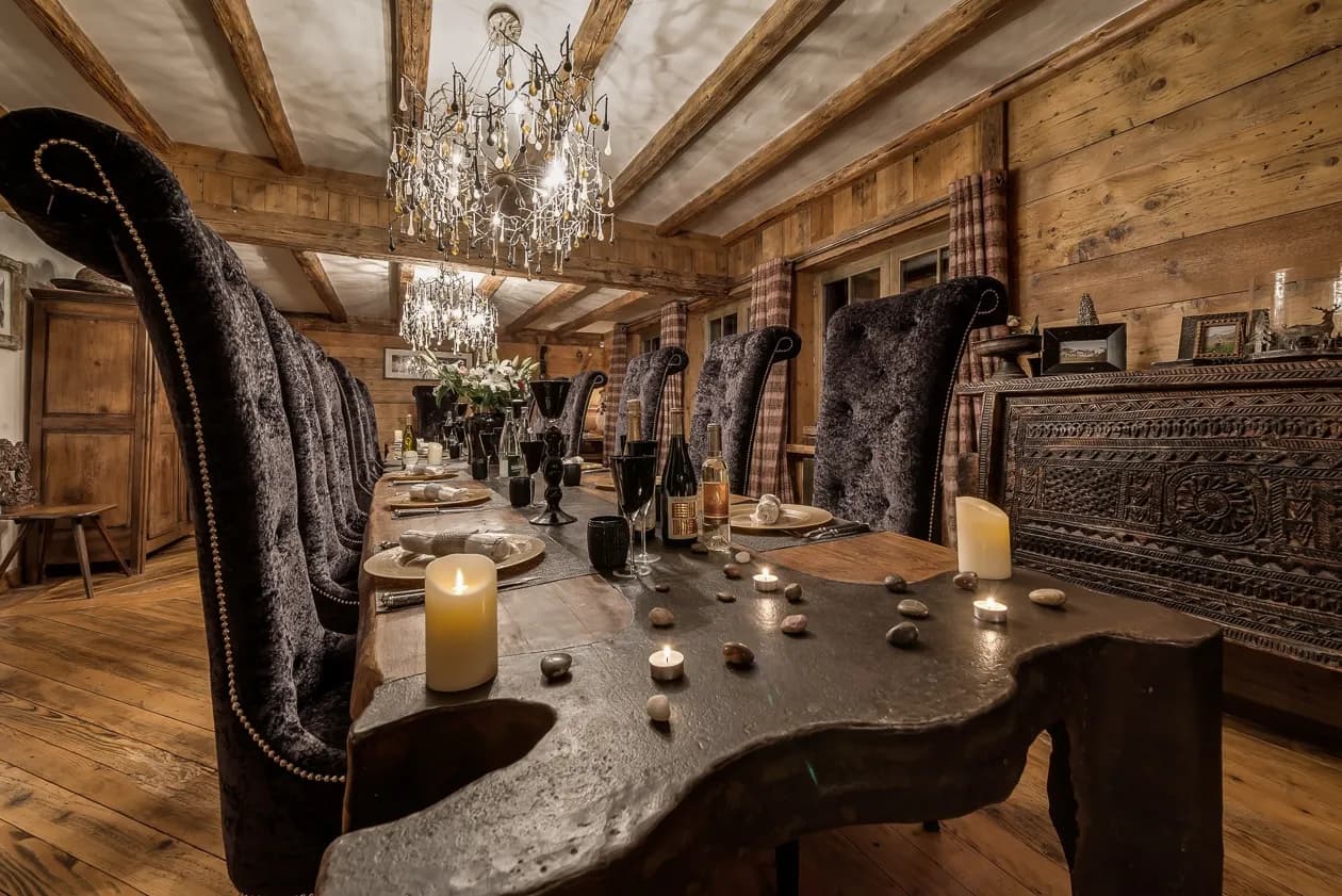 Dining table beneath a chandelier beside the lounge