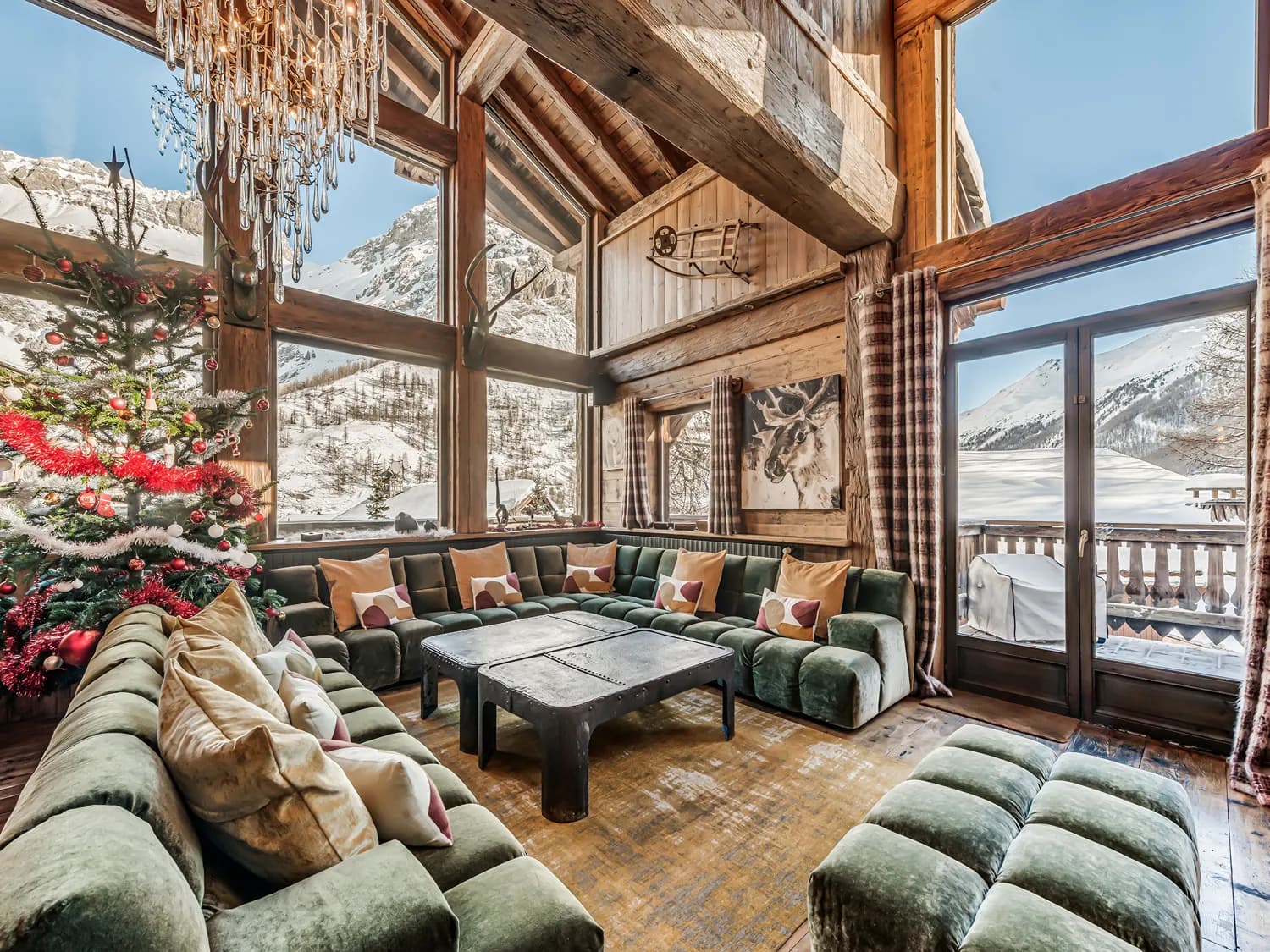 Vaulted lounge with green sofas and mountain-facing windows