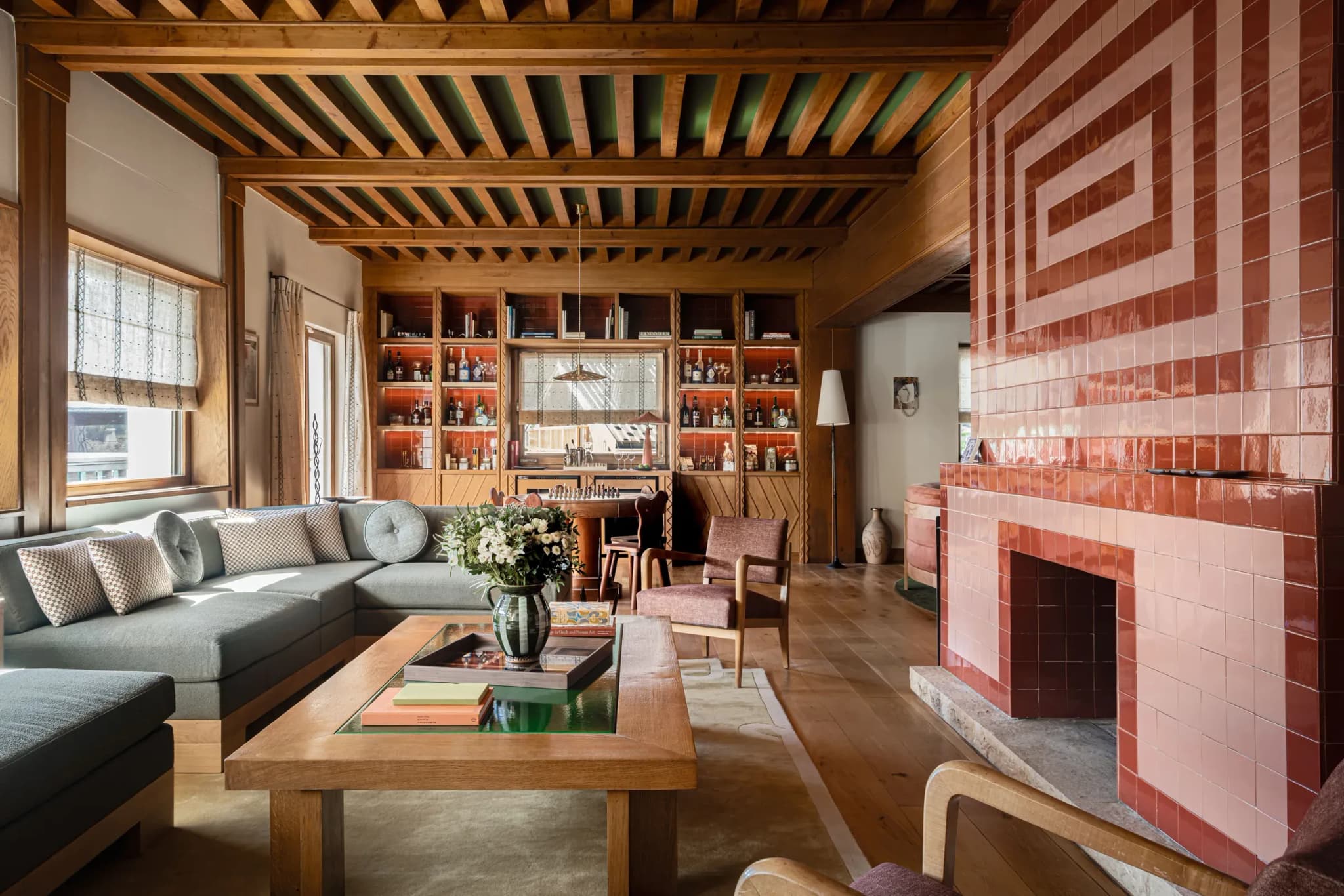 Living room with tiled fireplace, grey corner sofa and shelving with bar bottles