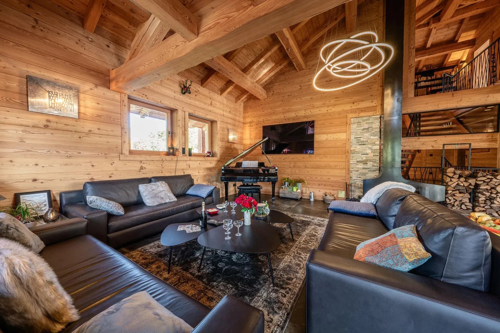 Living room with leather sofas, grand piano and central steel fireplace