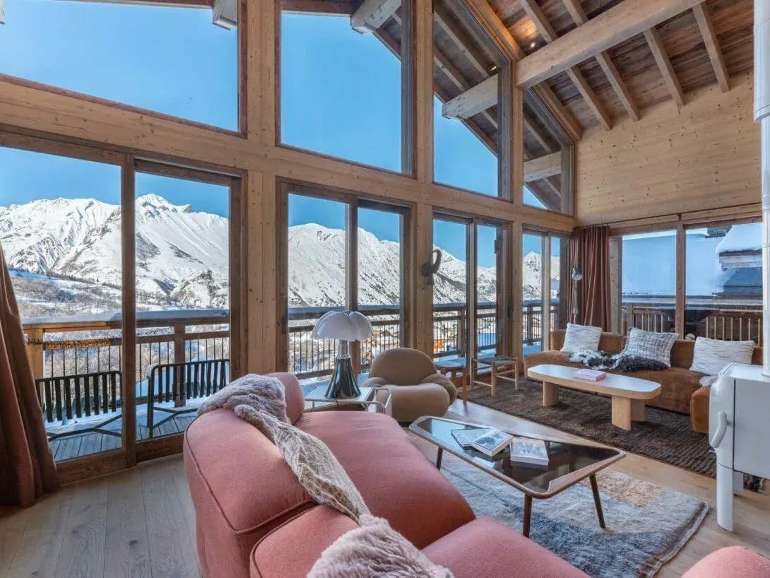 Living room with double-height windows, two sofas and snowy mountain views