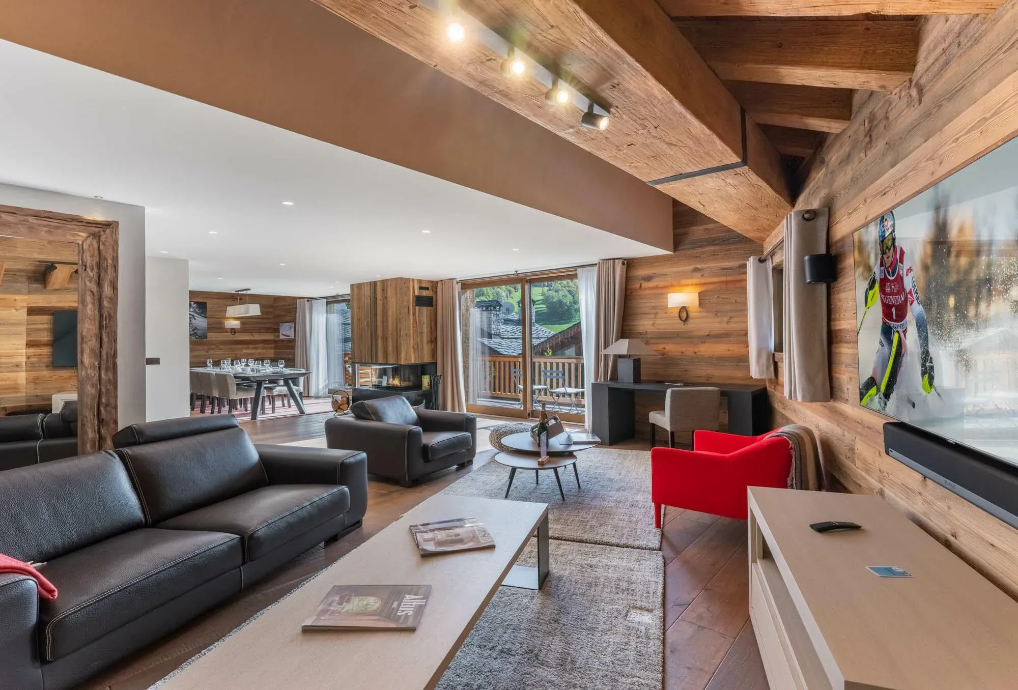 Open-plan lounge with leather sofas, wall-mounted TV and view through to dining table