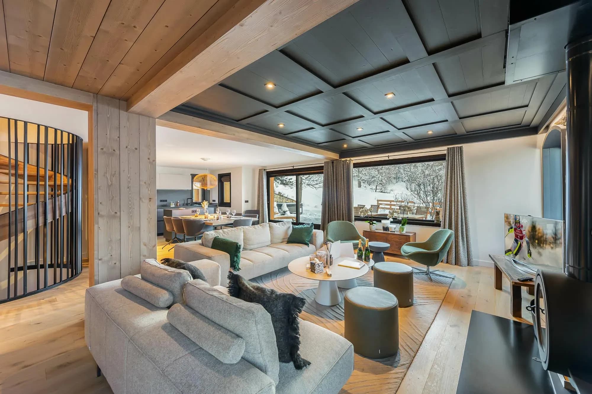 Lounge with corner sofa, green armchairs and spiral staircase beside the dining area
