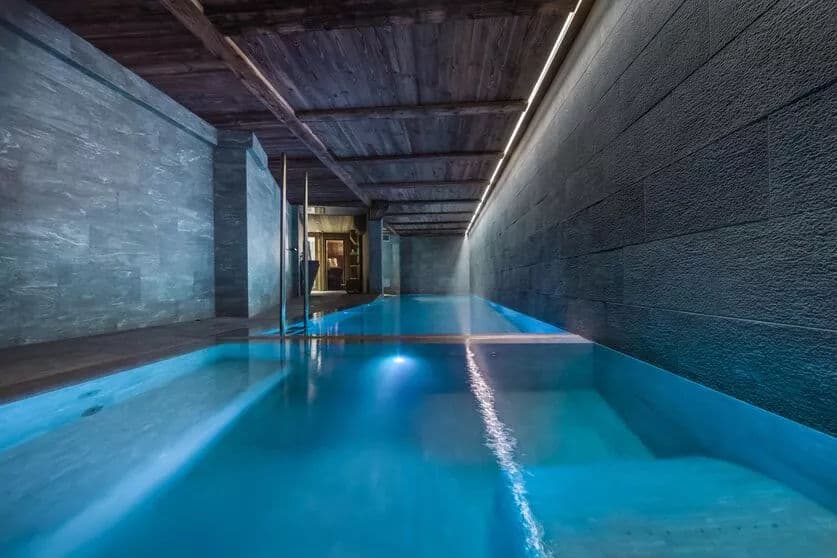 Indoor swimming pool with dark stone walls and blue lighting