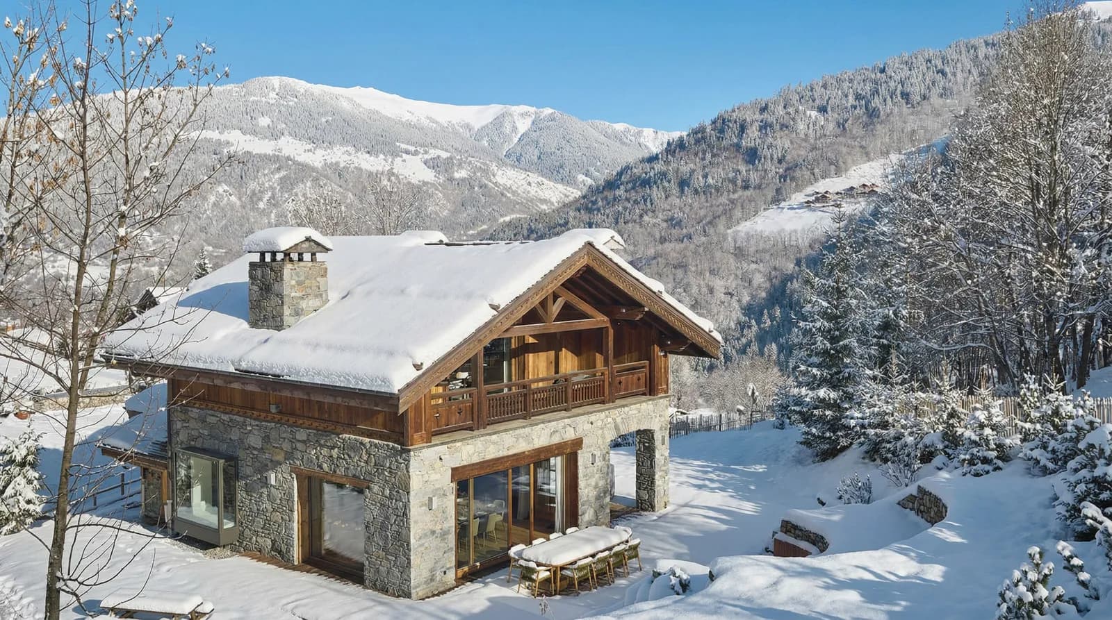 Snow-covered stone-and-timber chalet against forested mountain slopes
