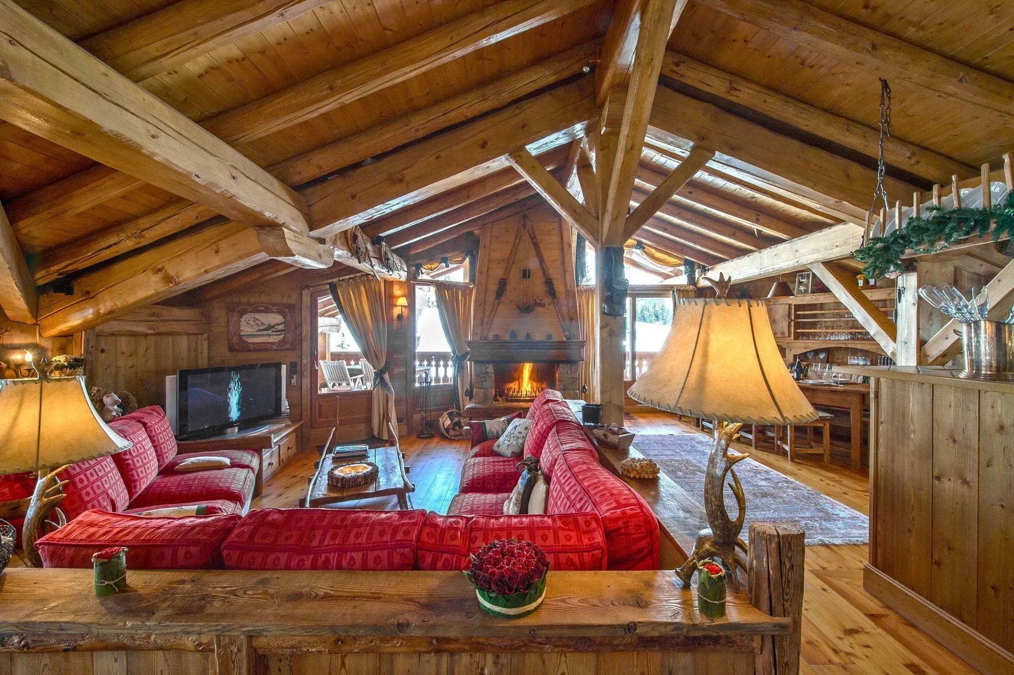 Open-plan living area with red sofas, wood fireplace and exposed beams