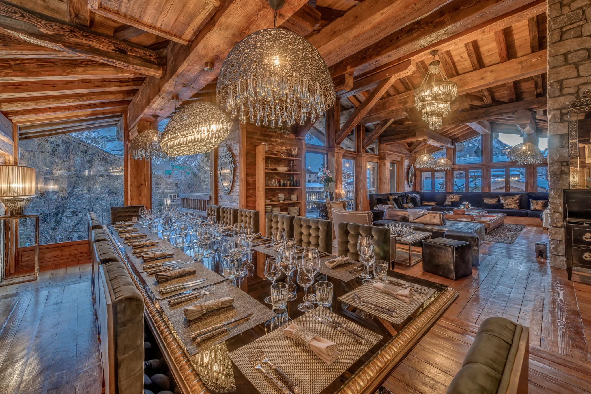 Dining table beneath chandeliers and exposed timber beams