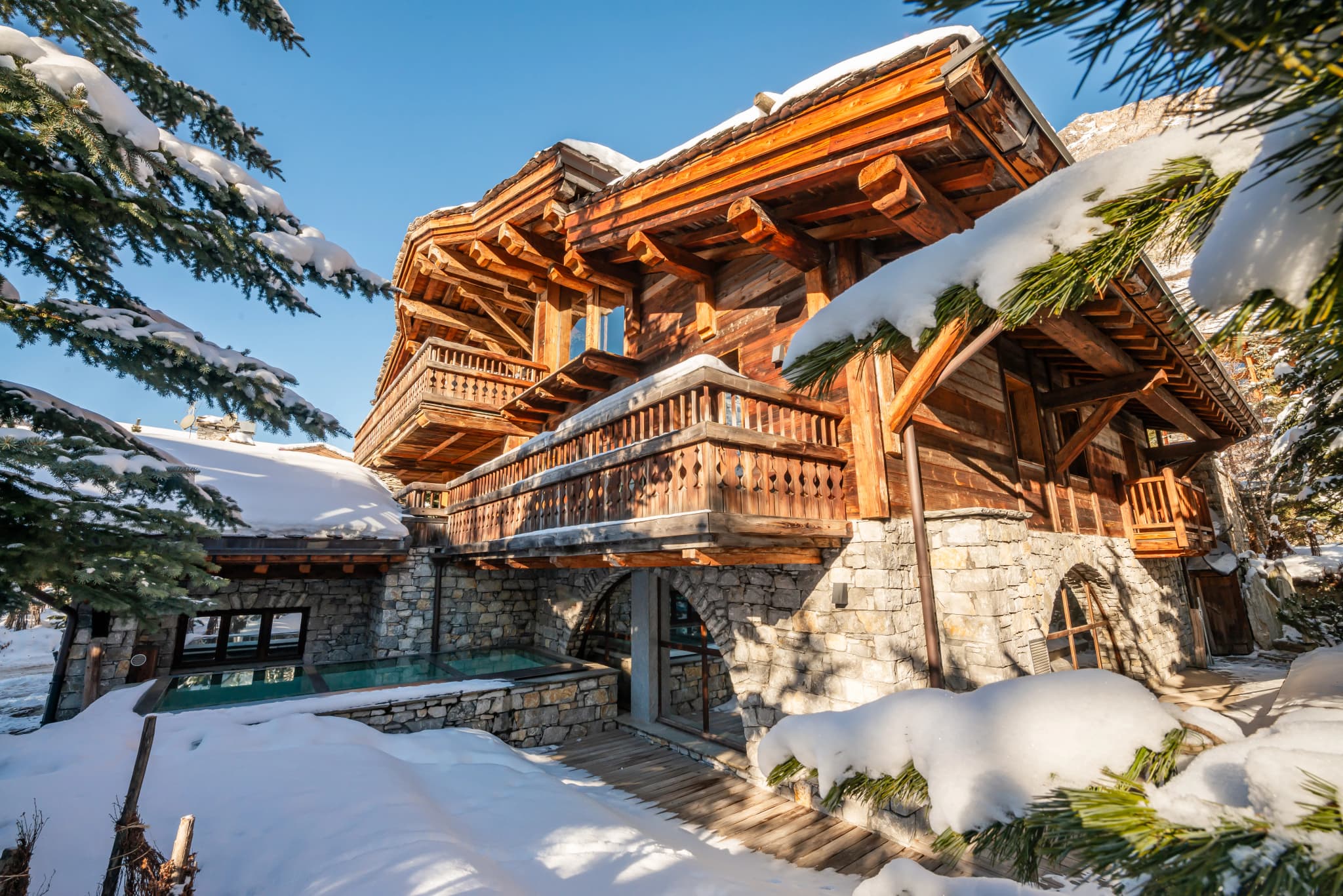 Snow-covered timber chalet framed by evergreen branches
