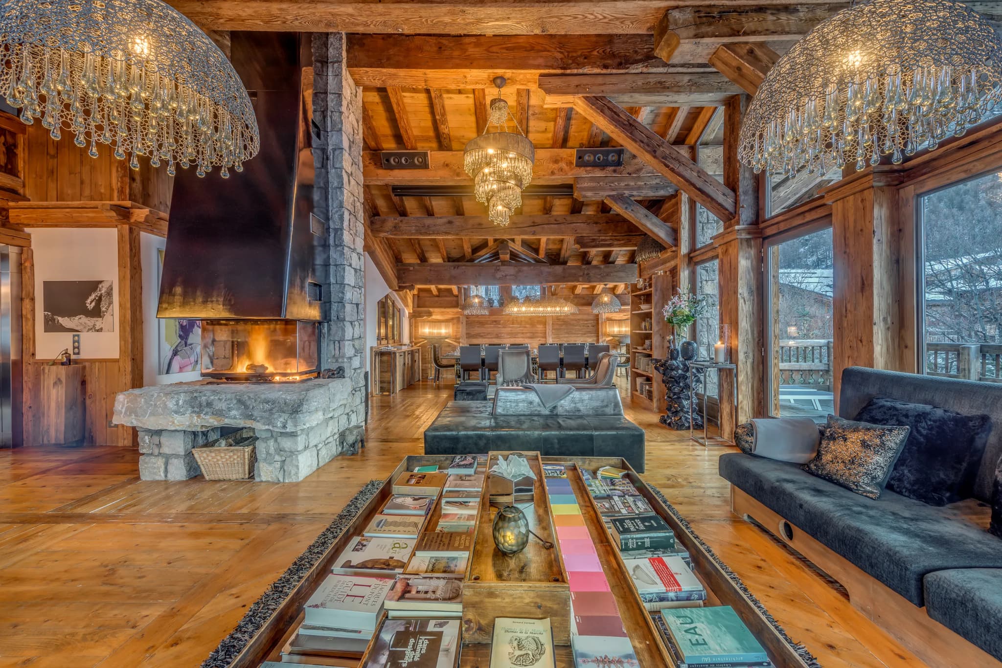 Living room with exposed beams, stone fireplace and chandelier lighting