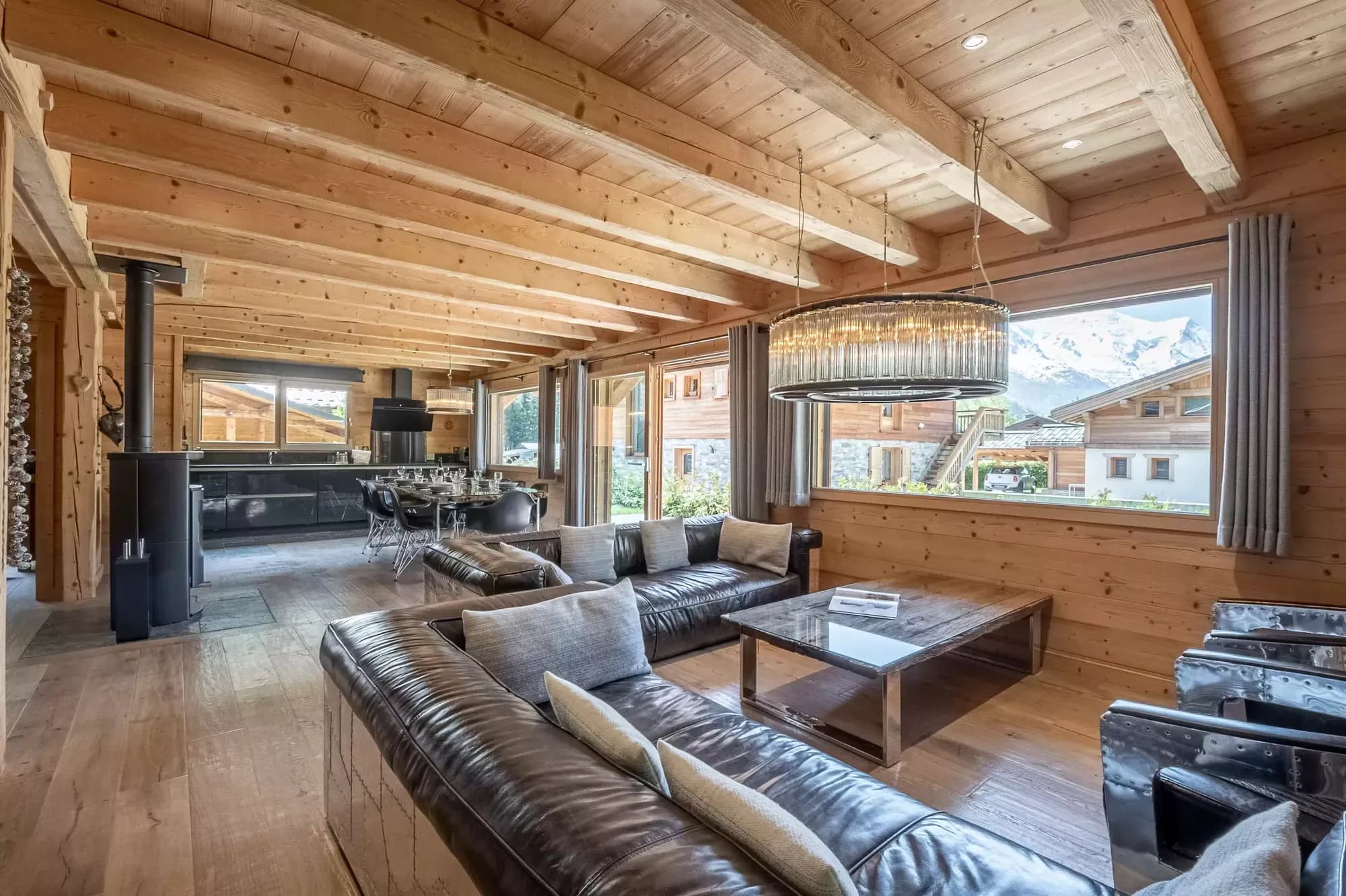 Open-plan timber lounge with sofas, broad windows and a wood stove