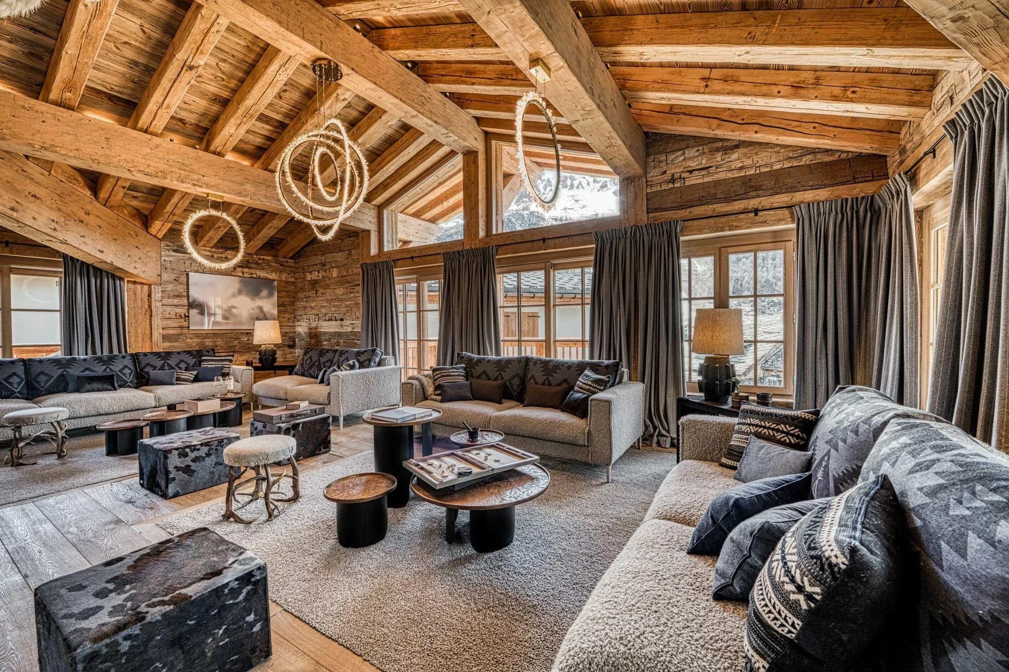Lounge with three sofas, cowhide ottomans and exposed beams under a vaulted ceiling