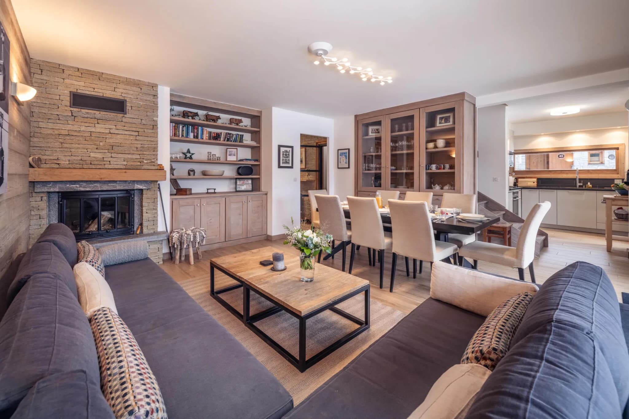 Living area with grey sofas, stone fireplace and dining table behind