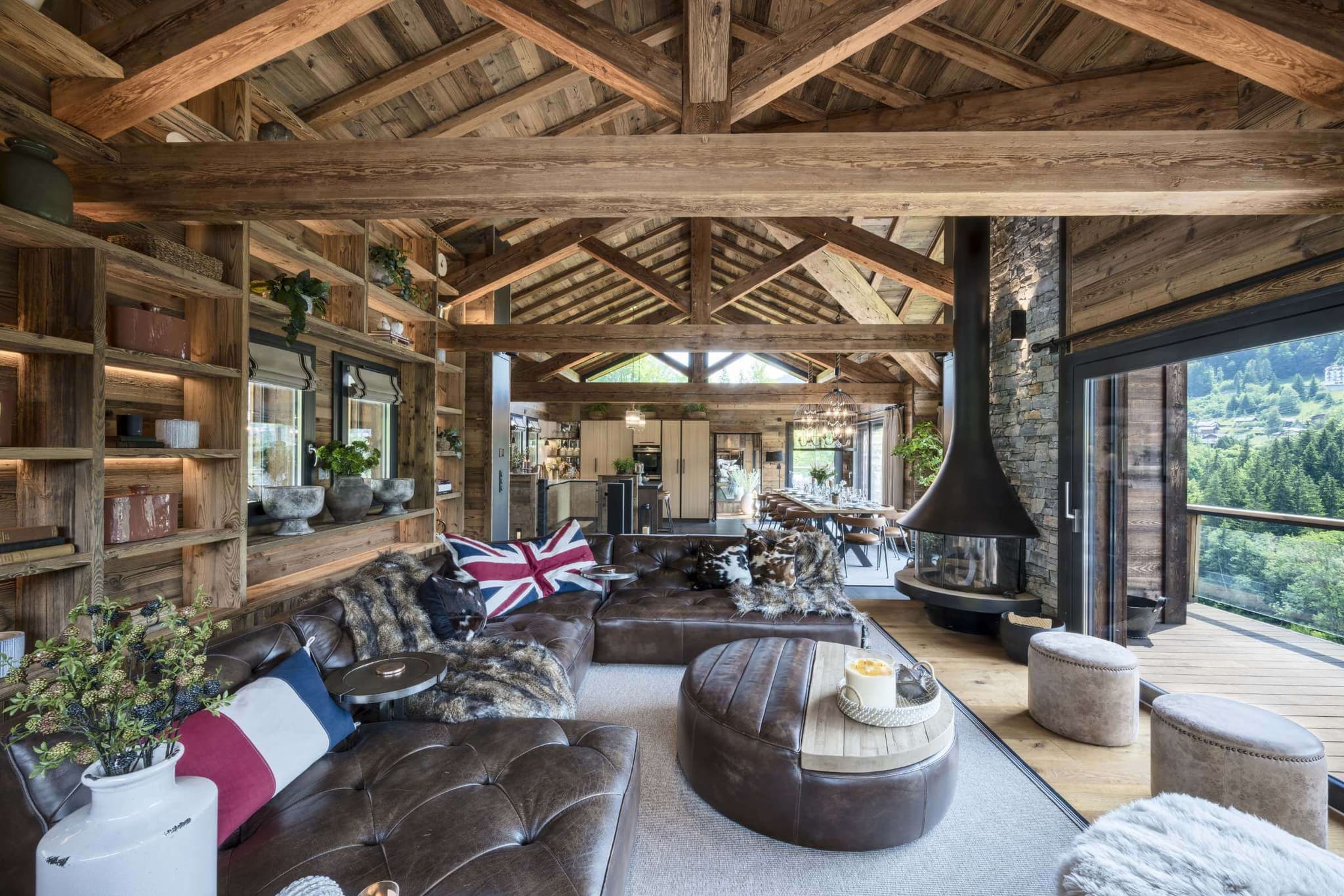 Open-plan living area with leather seating, a wood-burning stove and mountain views