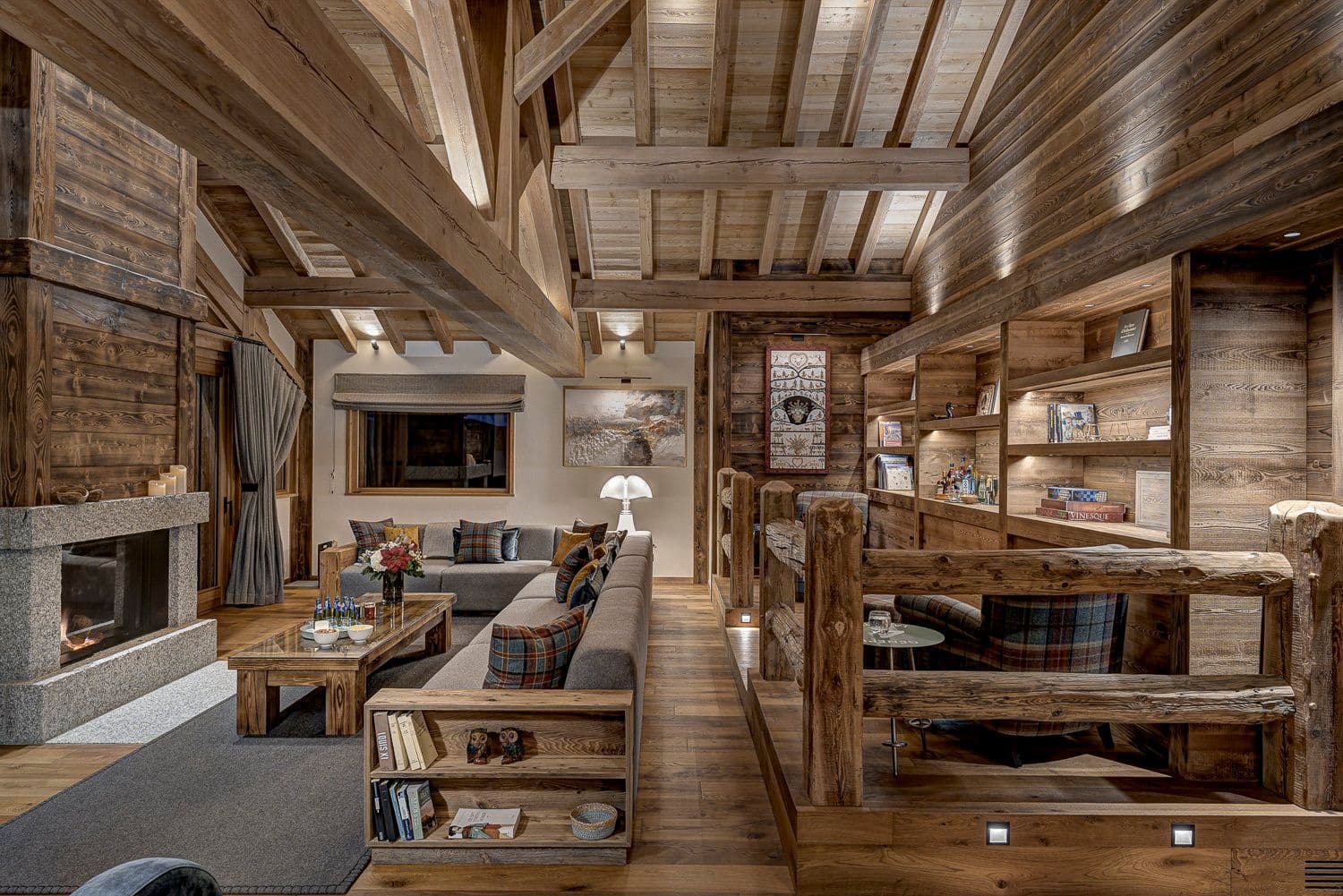 Open-plan living room with exposed beam ceilings, fireplace, and built-in shelving throughout