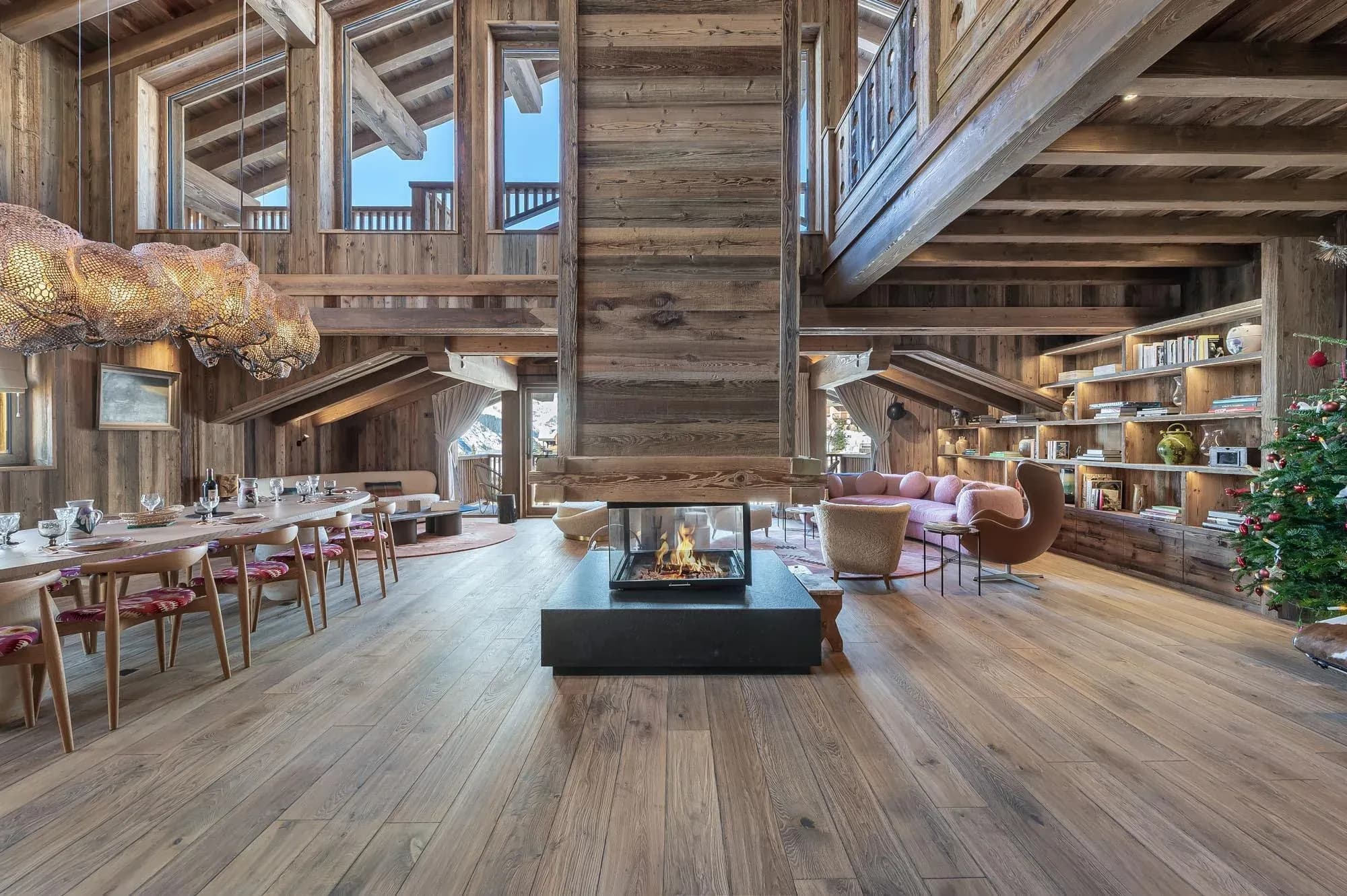 Open-plan living and dining area with central glass-sided fireplace and long table