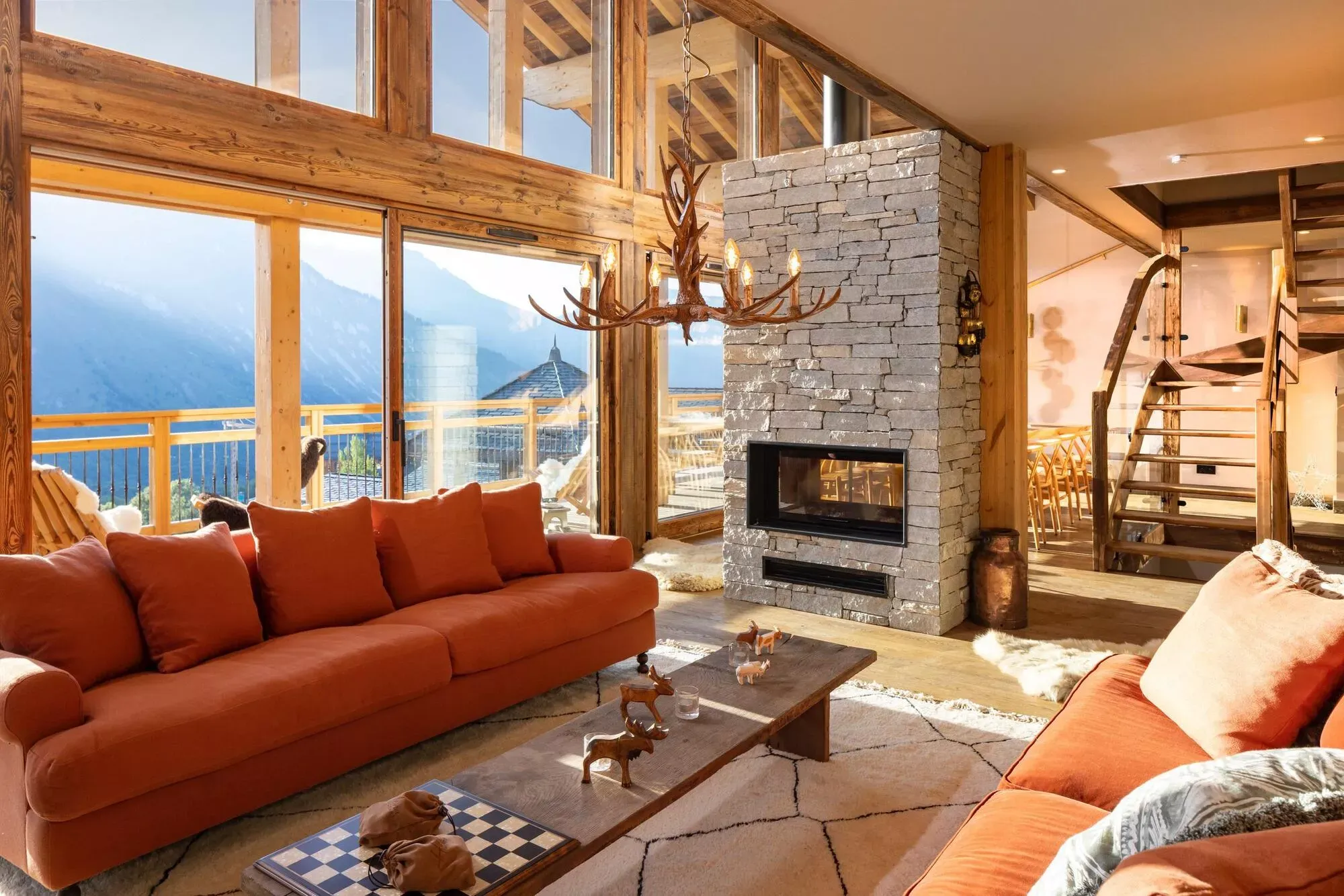 Living room with central glass-sided fireplace and mountain-facing windows