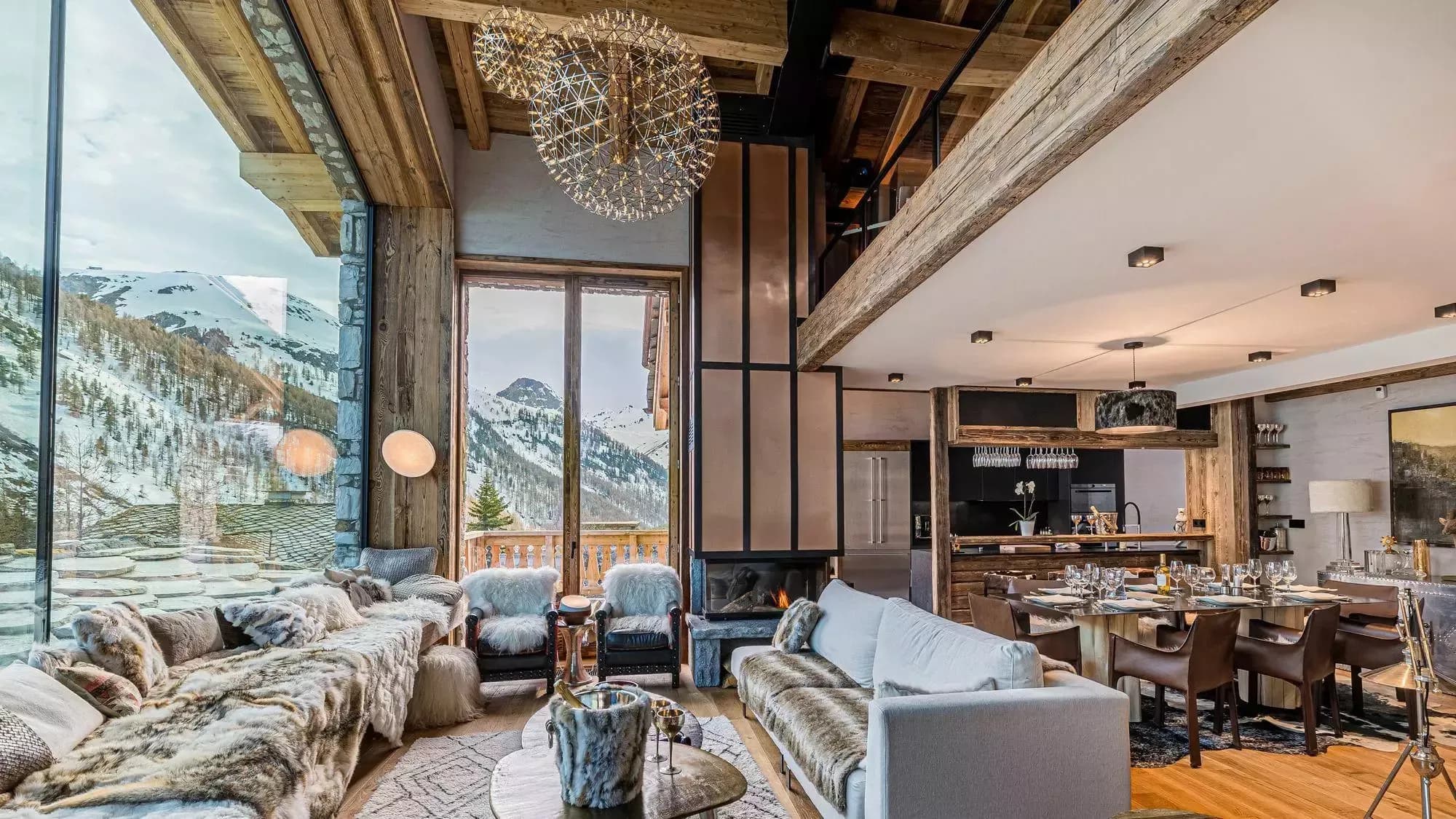 Double-height living and dining room with mountain views through floor-to-ceiling windows