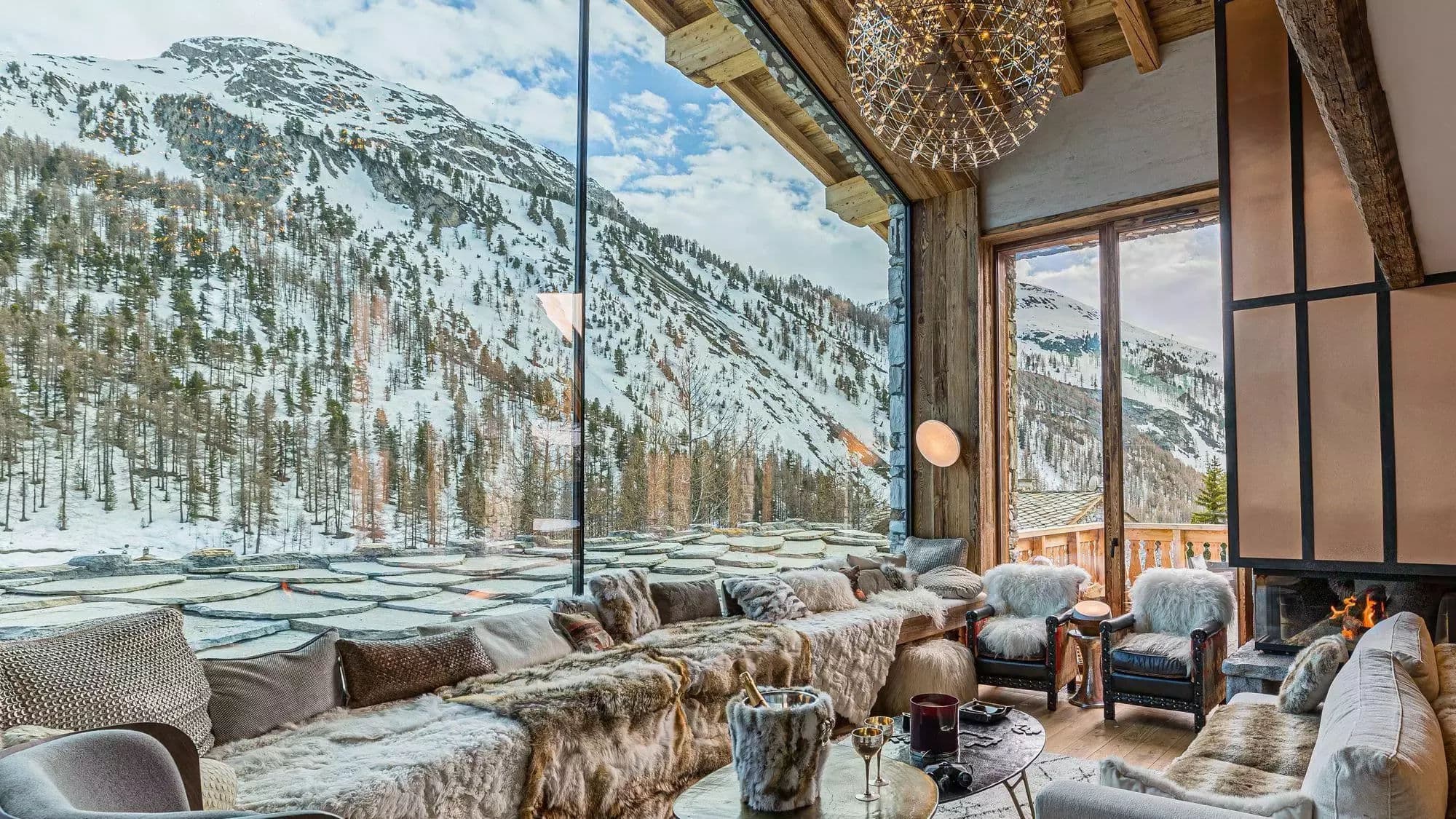 Living room seating beside the three-sided fireplace and panoramic windows