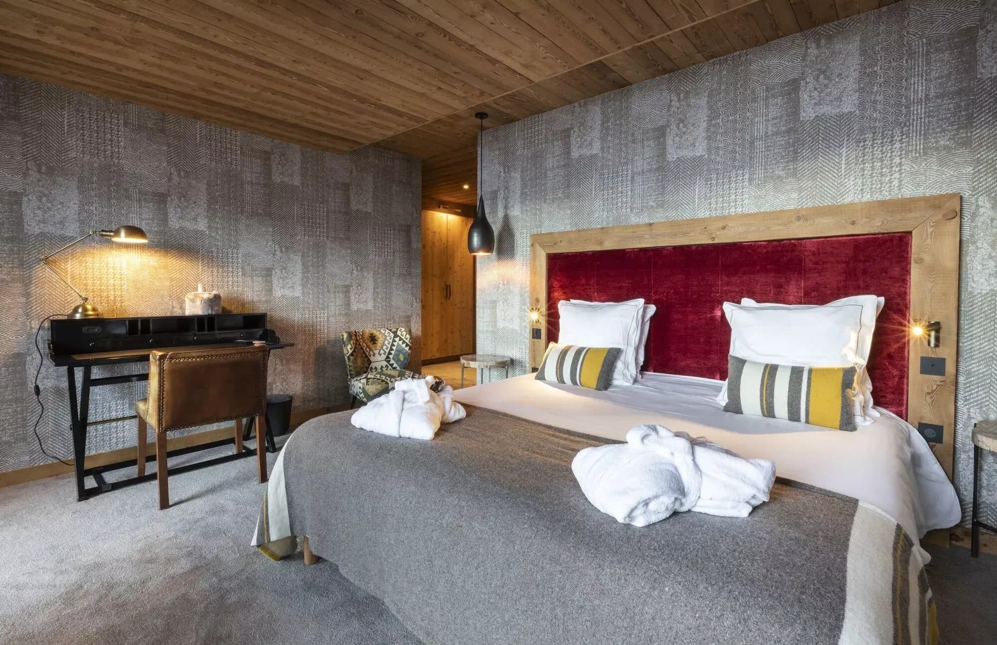 Double bedroom with red upholstered headboard, desk and mountain view