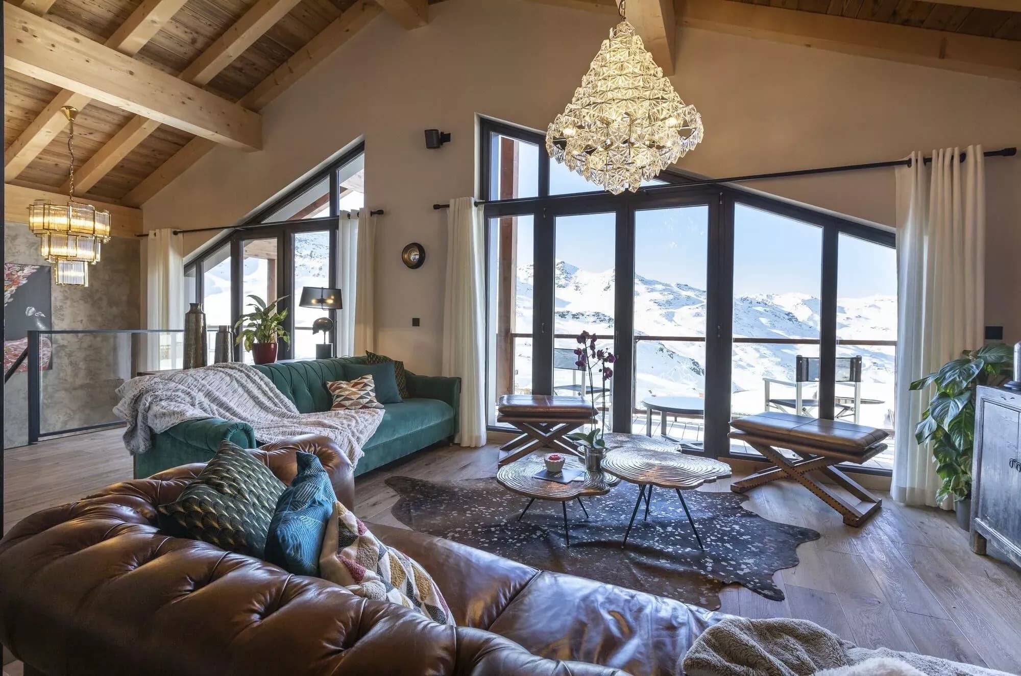 Living room with lounge seating, central fireplace and mountain-facing windows