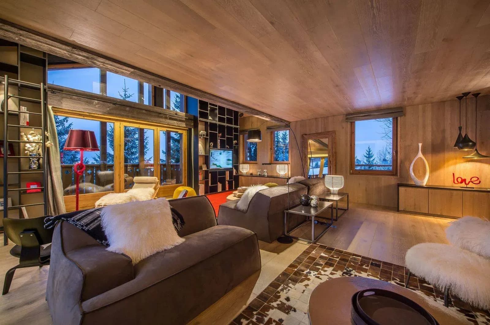 Open-plan living area with multiple seating zones and forest views through expansive windows