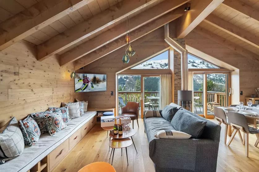 Timber-lined living room with sofas, television and mountain-view windows