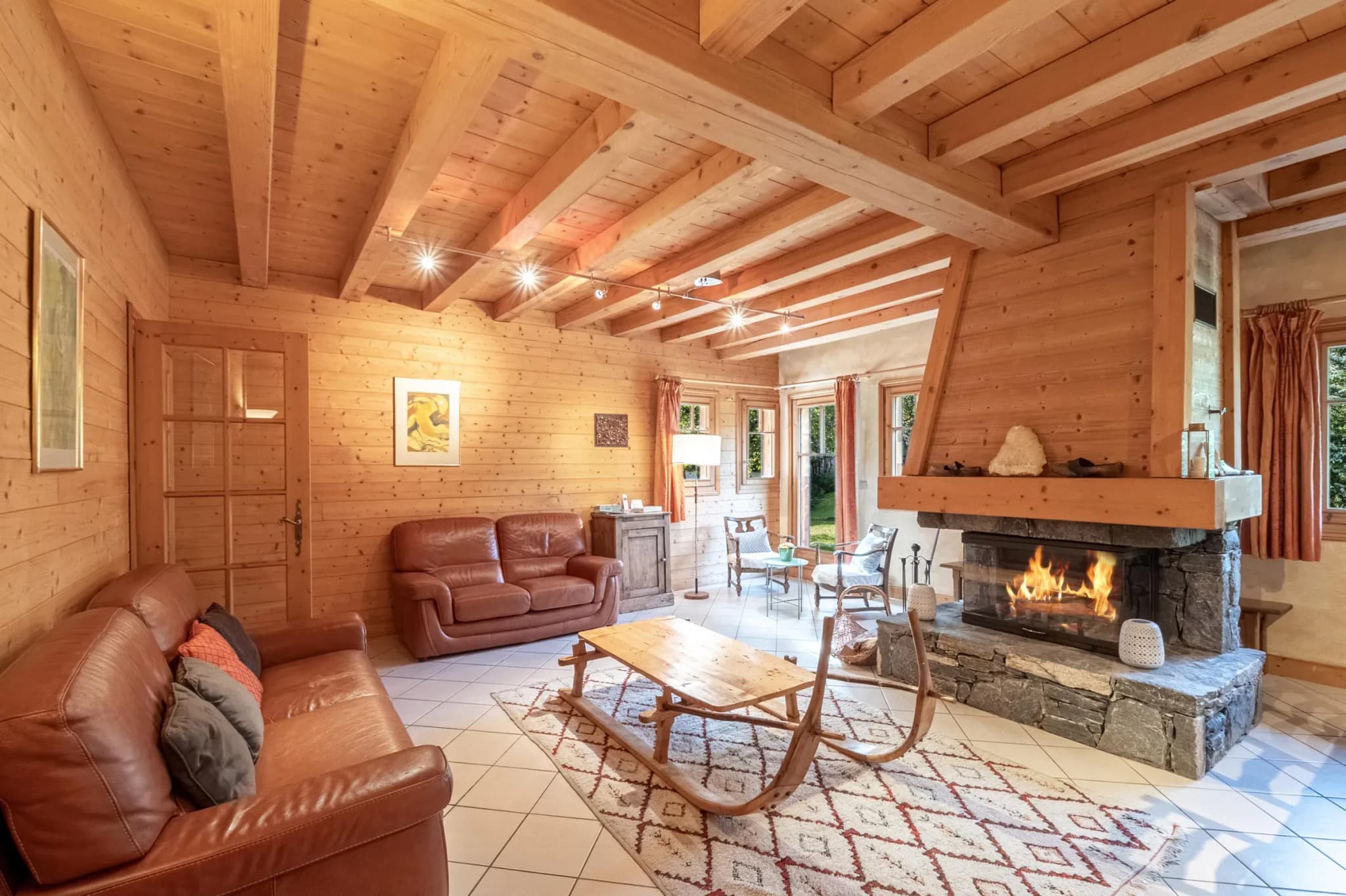 Living room with stone fireplace, two leather sofas and sledge coffee table
