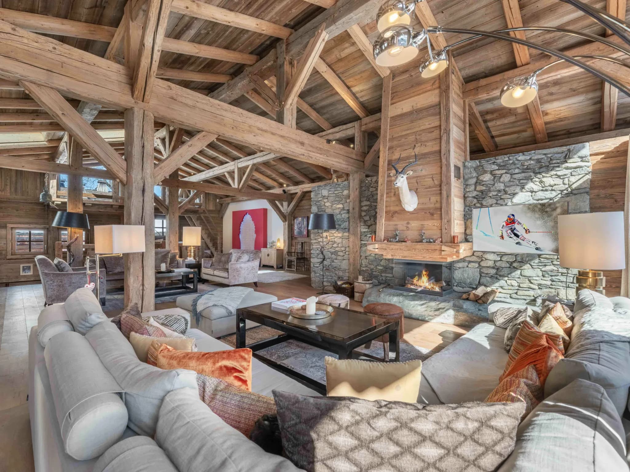 Lounge with large grey sofas facing a stone fireplace and ski artwork