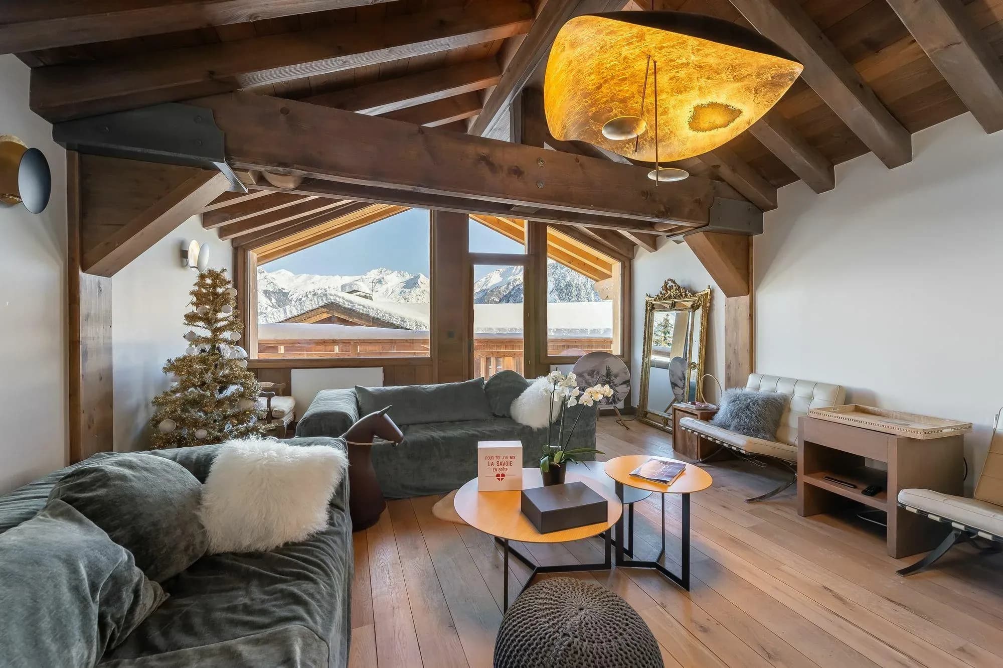 Living room with grey sofas, exposed beams and mountain views through the window