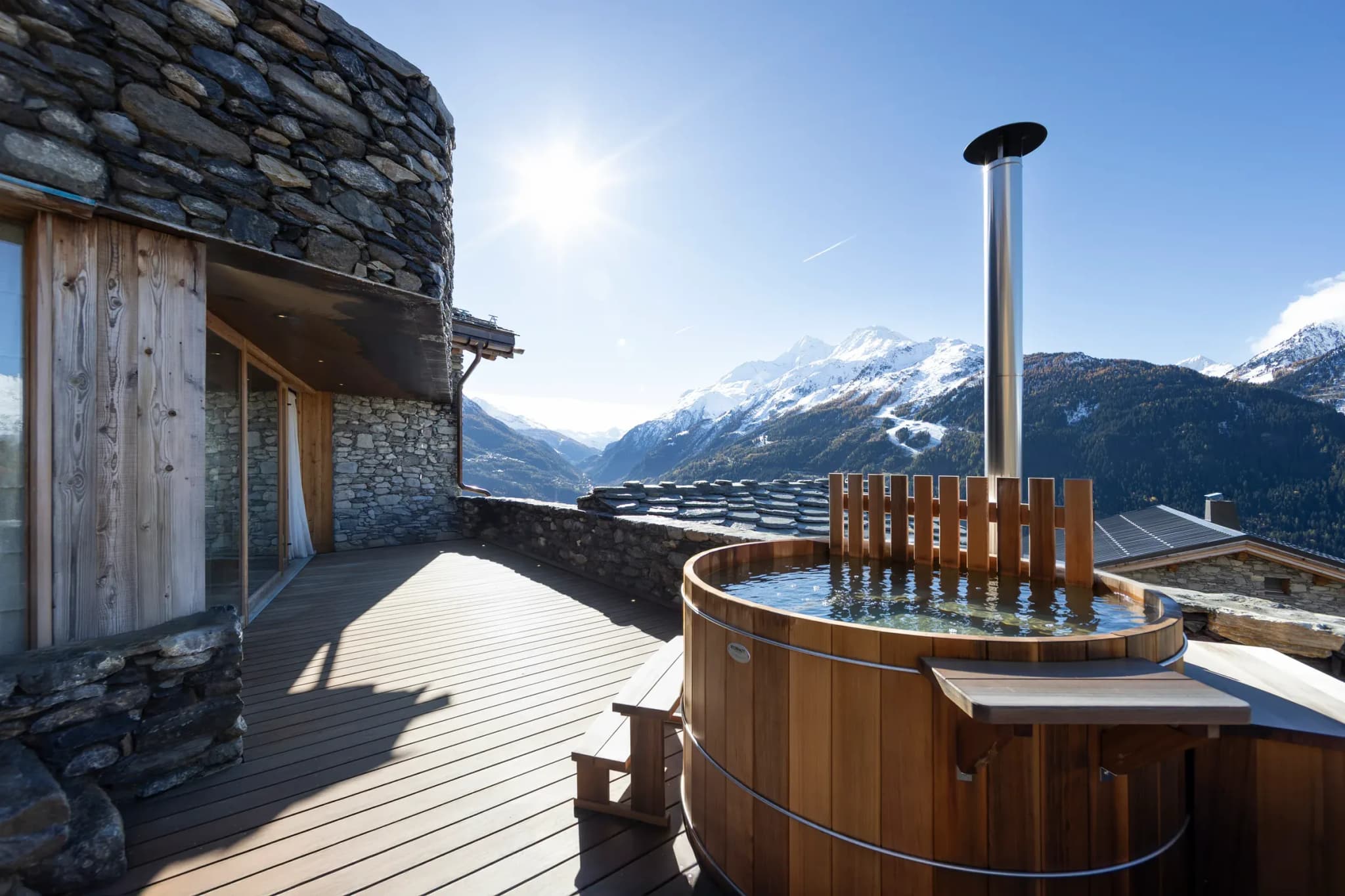 Terrace with wooden hot tub and snow-capped mountain view