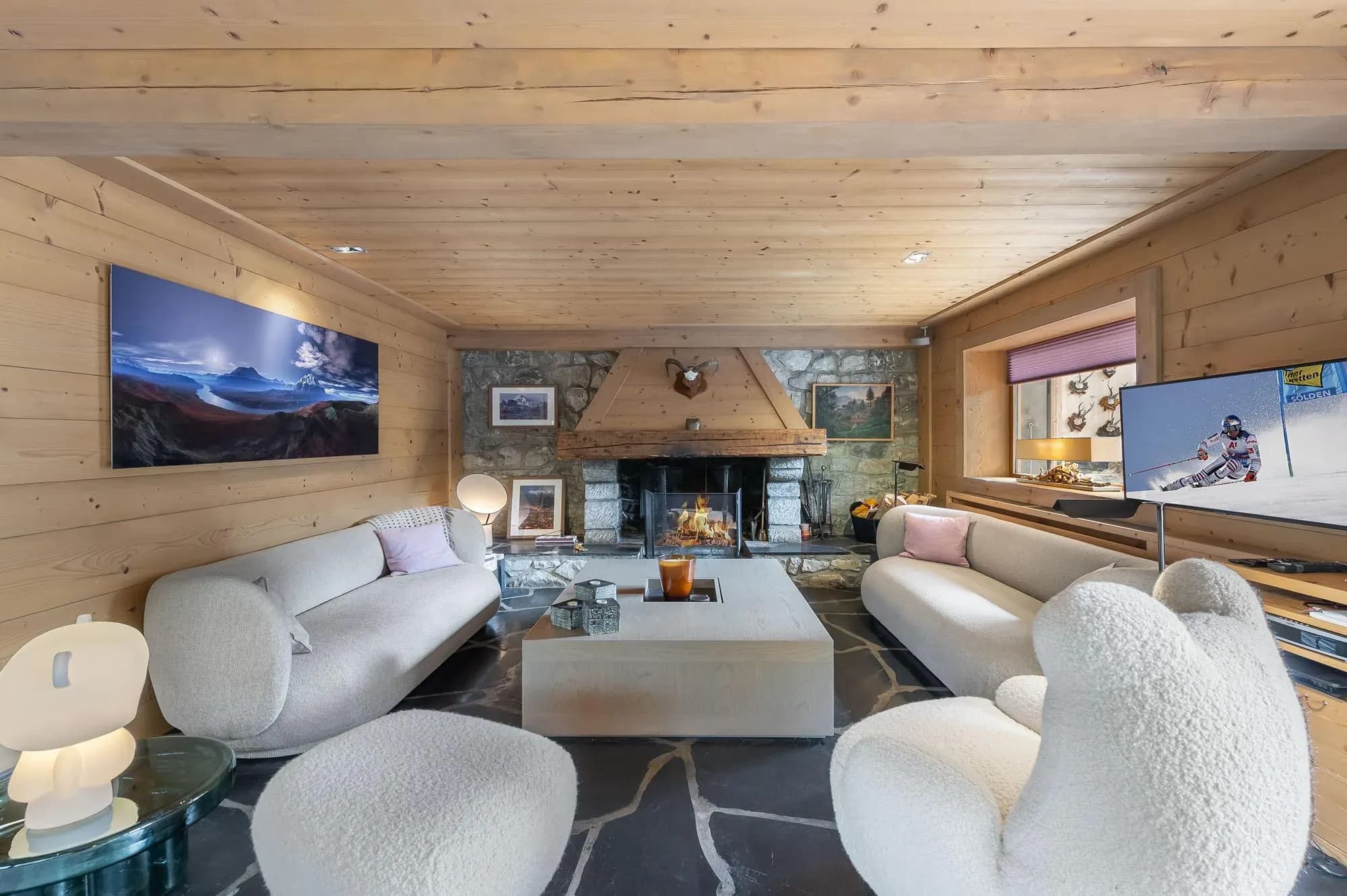 Living room with stone fireplace, two curved sofas and boucle armchairs