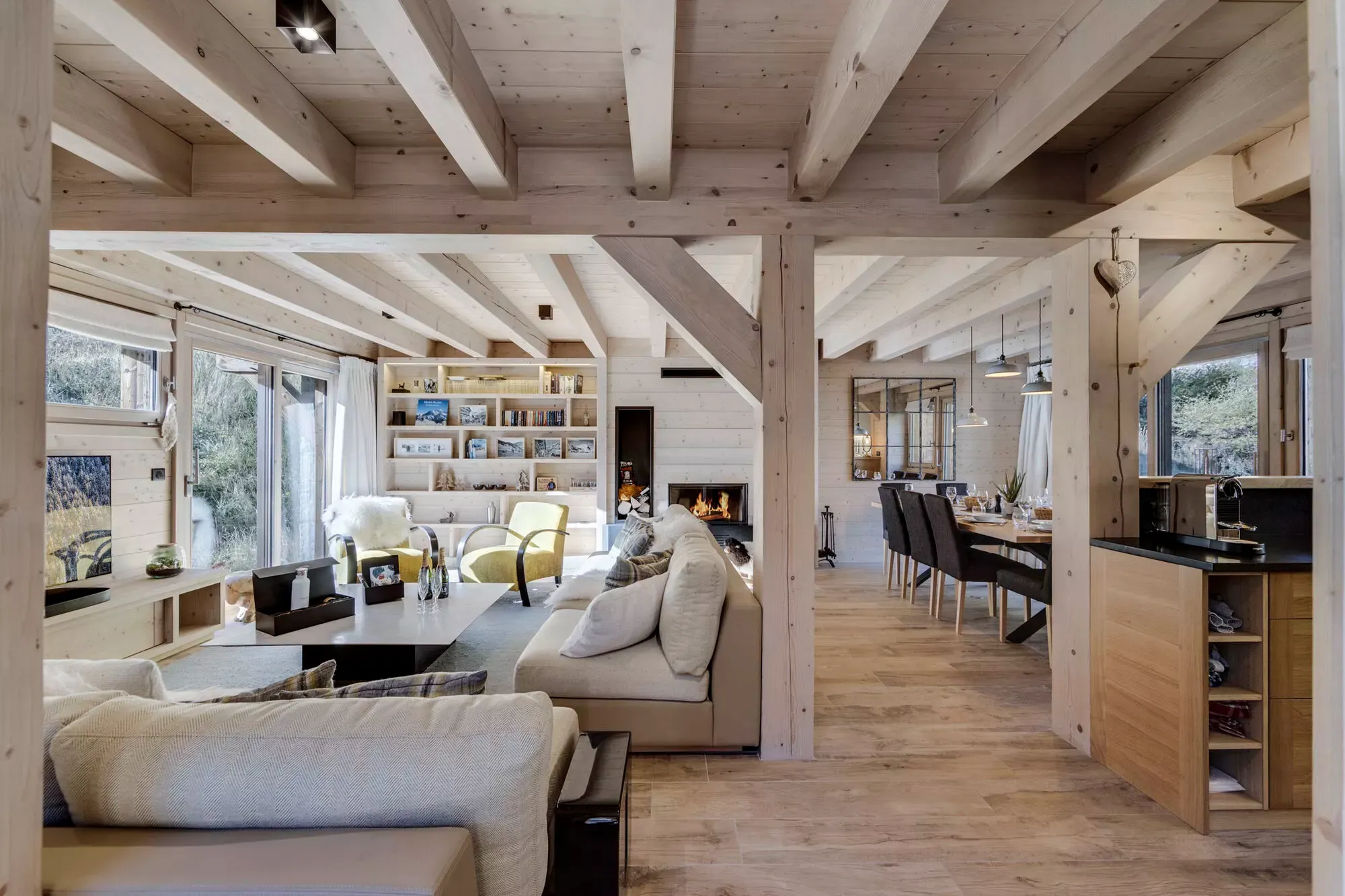 Open-plan living and dining area beneath pale timber beams