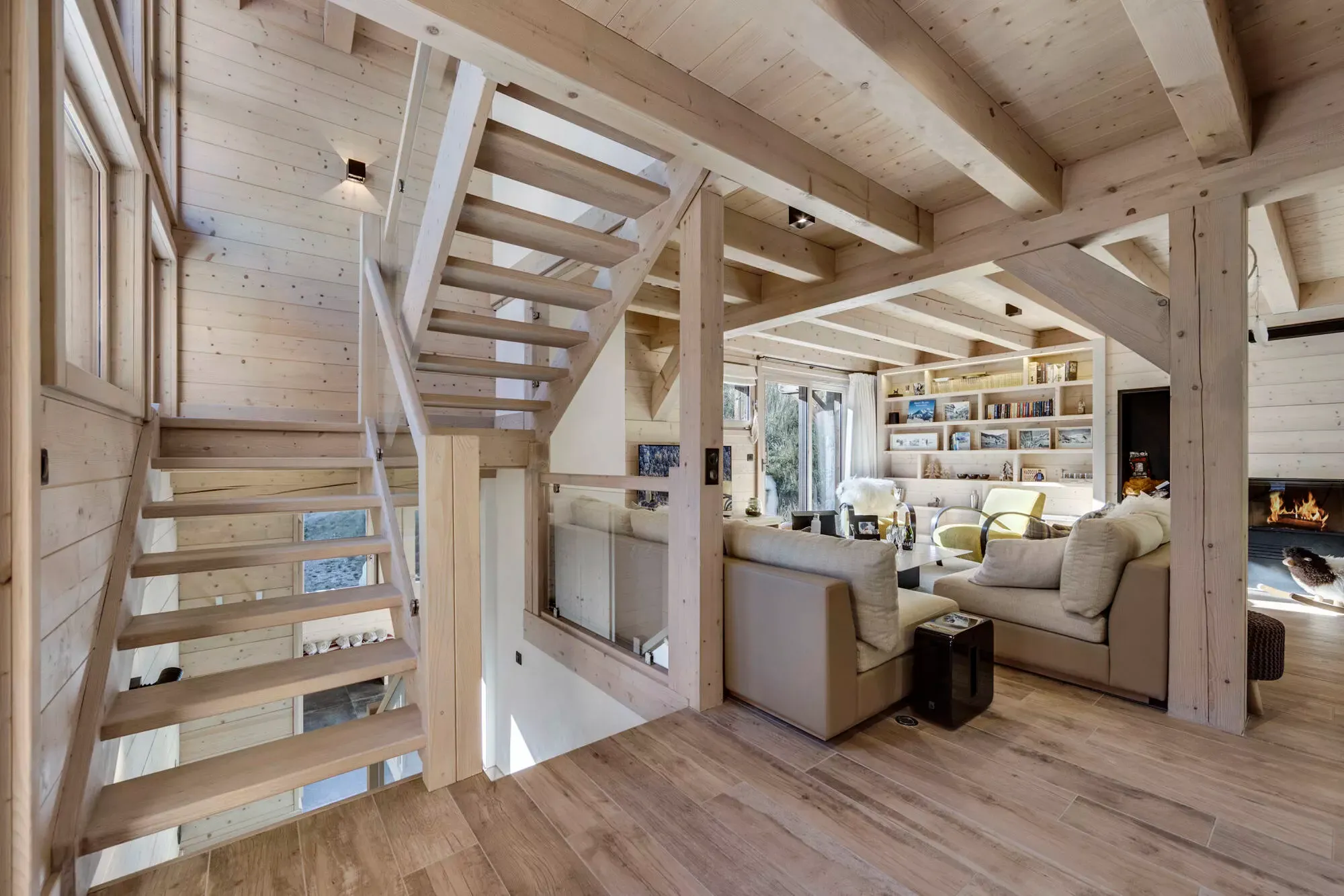 Timber staircase beside the bright living room and fireplace