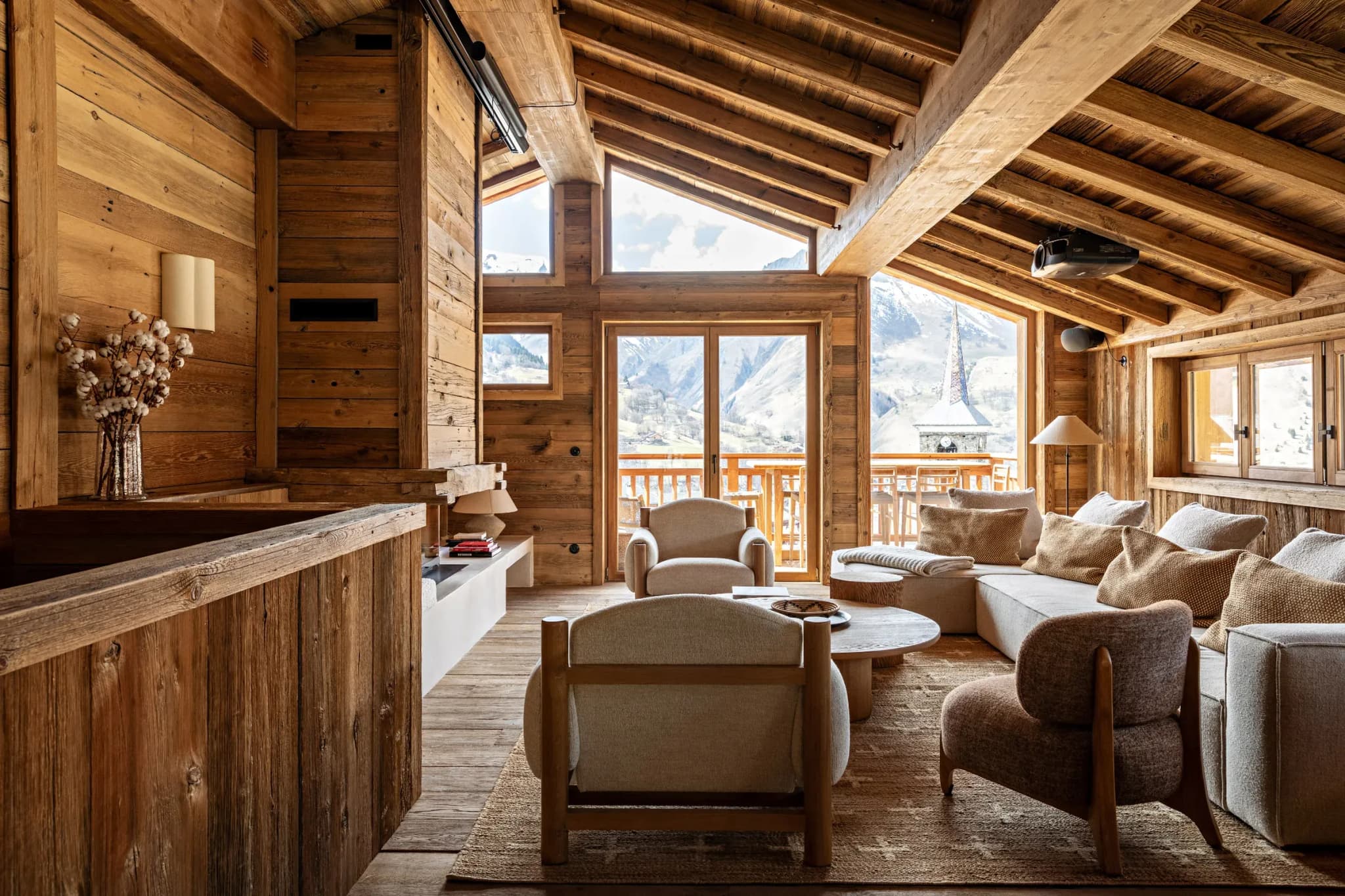 Lounge with corner sofa, armchairs and mountain view through glass doors