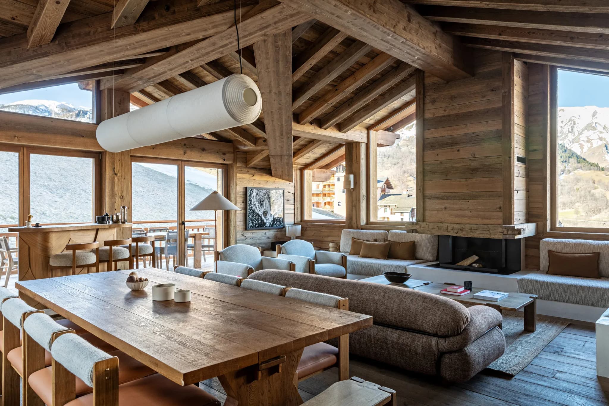 Open-plan lounge with fireplace, corner sofas and dining table seating eight under exposed beams