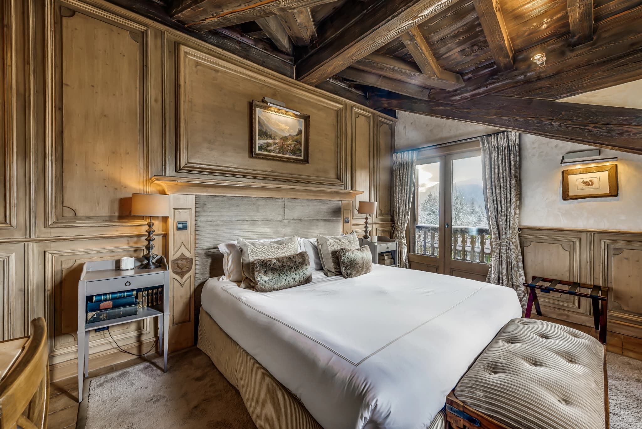 Double bedroom beneath timber beams with balcony doors