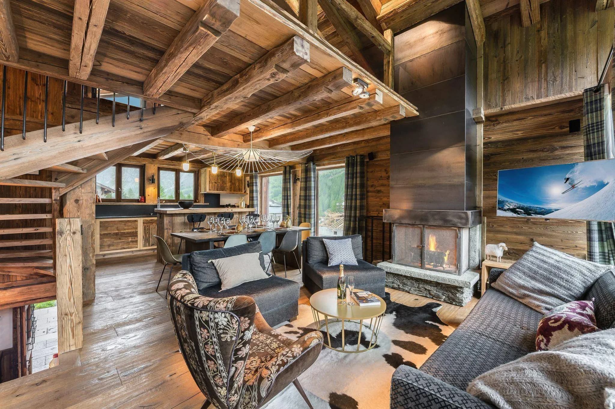 Living room with open wood fireplace, two sofas, armchairs and dining table behind