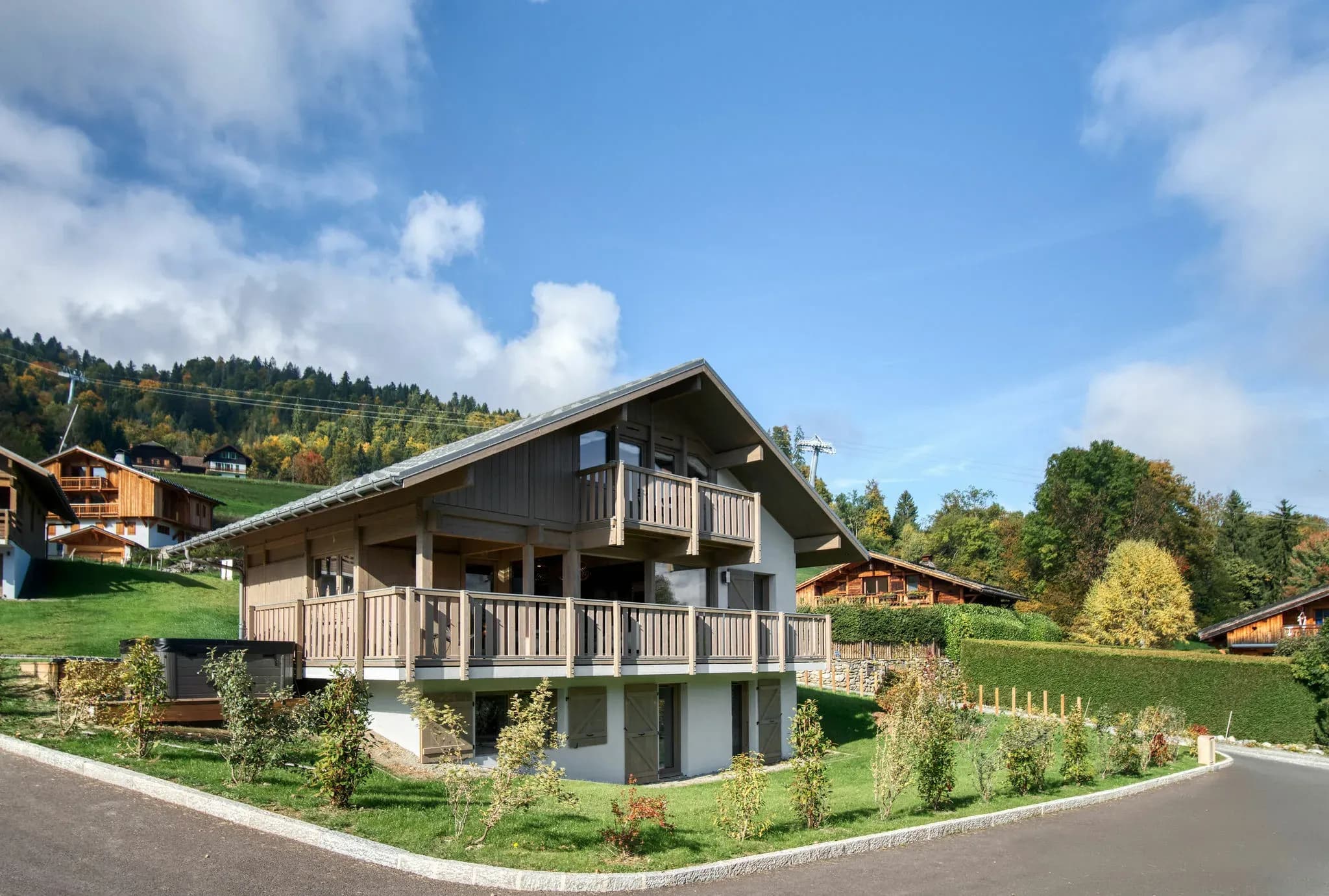 Chalet with wraparound wooden balconies, garden and hot tub beside the road